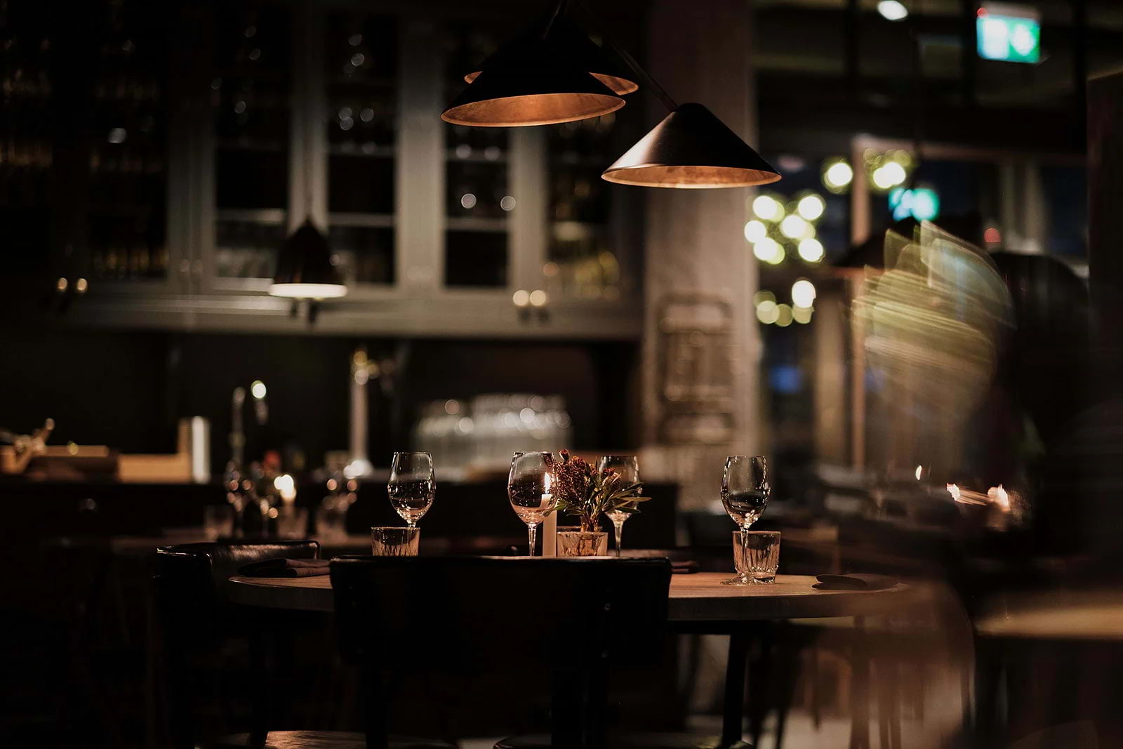 A candlelit restaurant table with wine glasses at night