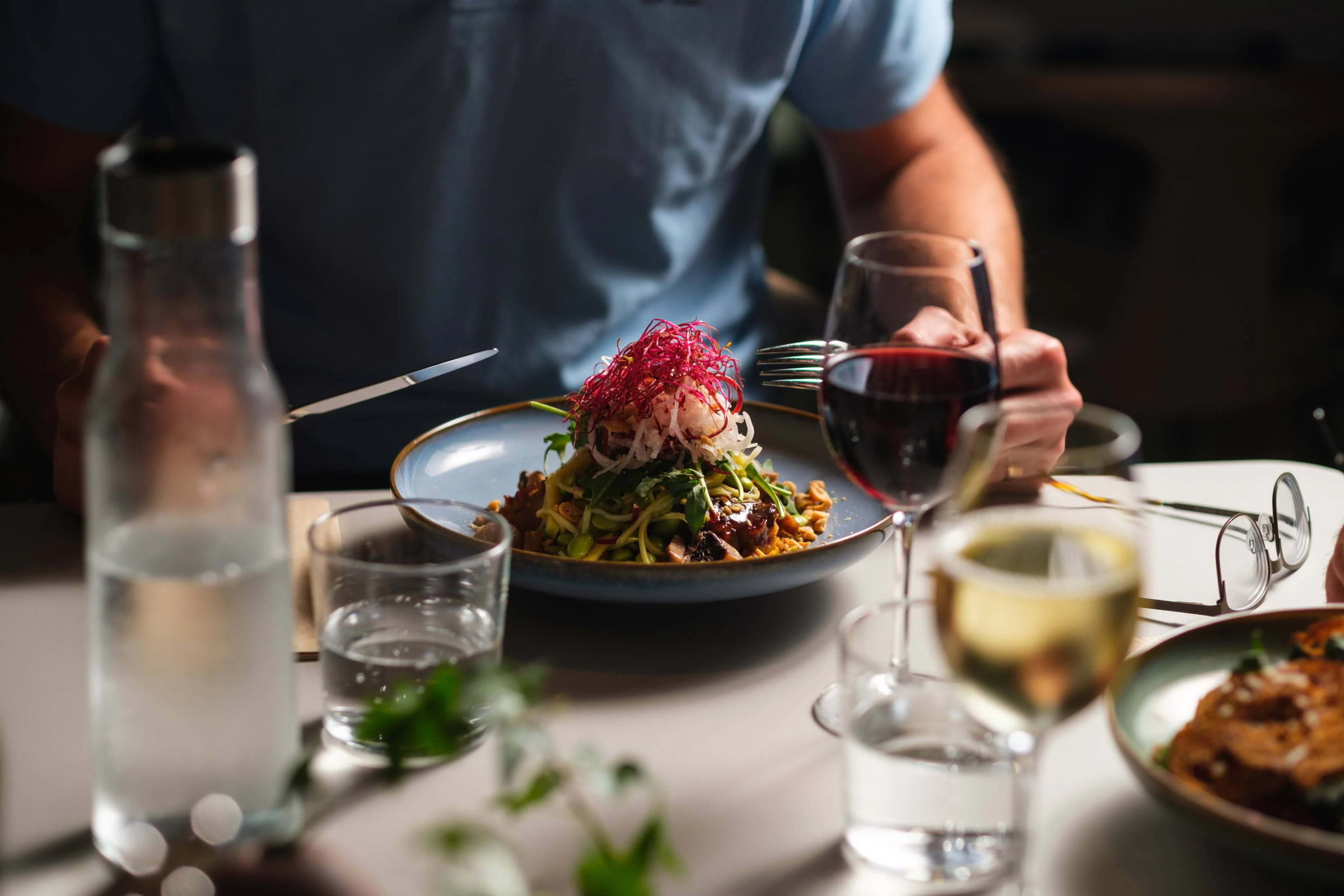 A restaurant guest holding a knife and fork over a plate of food