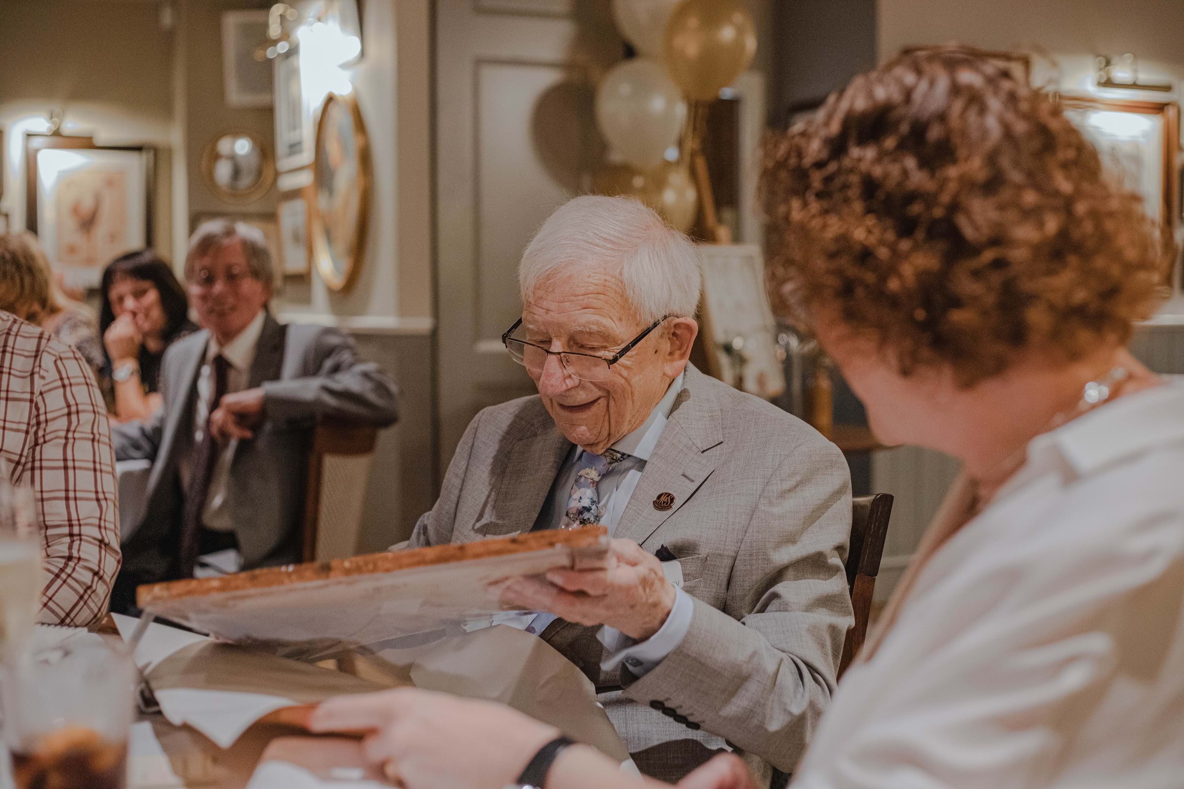 Elderly man opening a gift in a restaurant