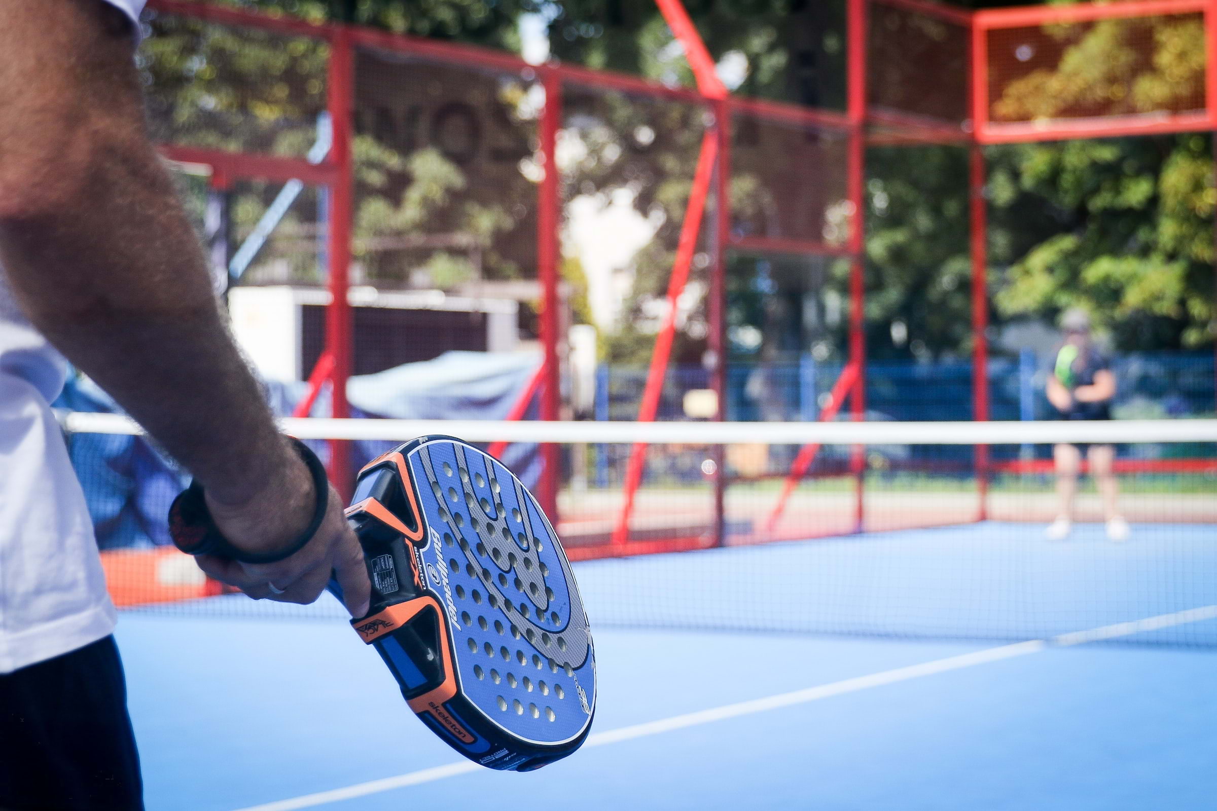 A man holding a padel racket on an outdoor court