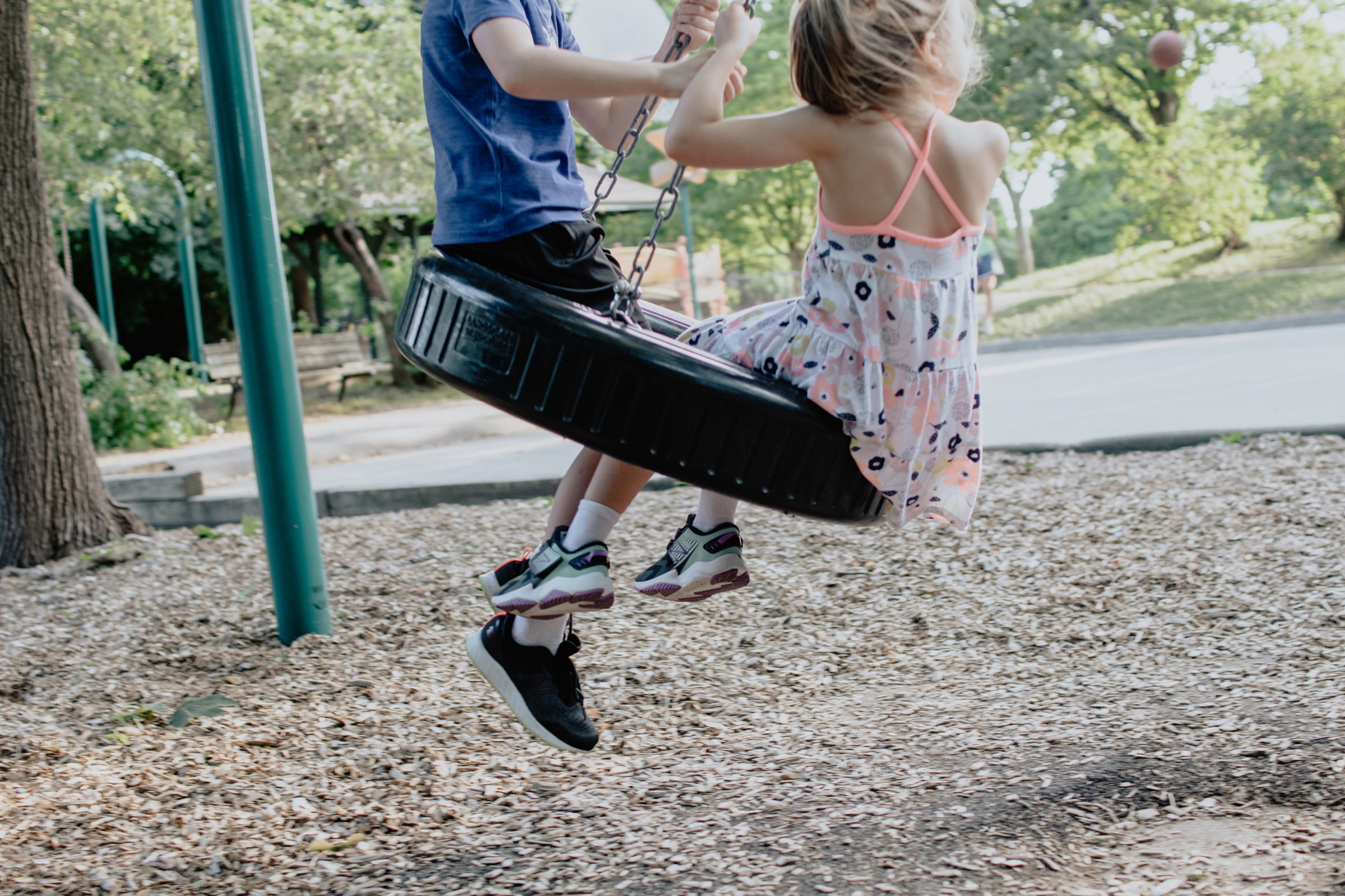 Two children on a swing in a playground
