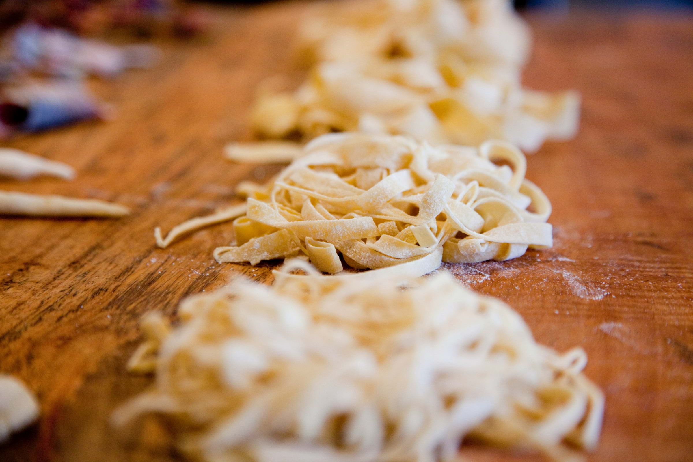 Piles of freshly made pasta on a wooden table