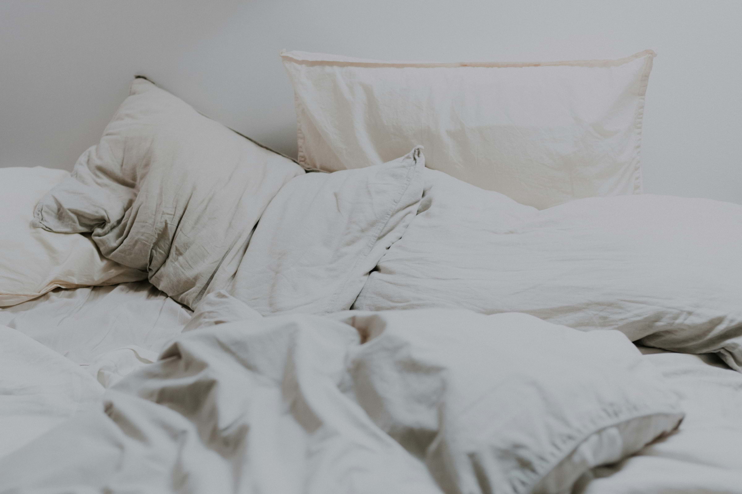 A white crumpled duvet and pillows on the bed