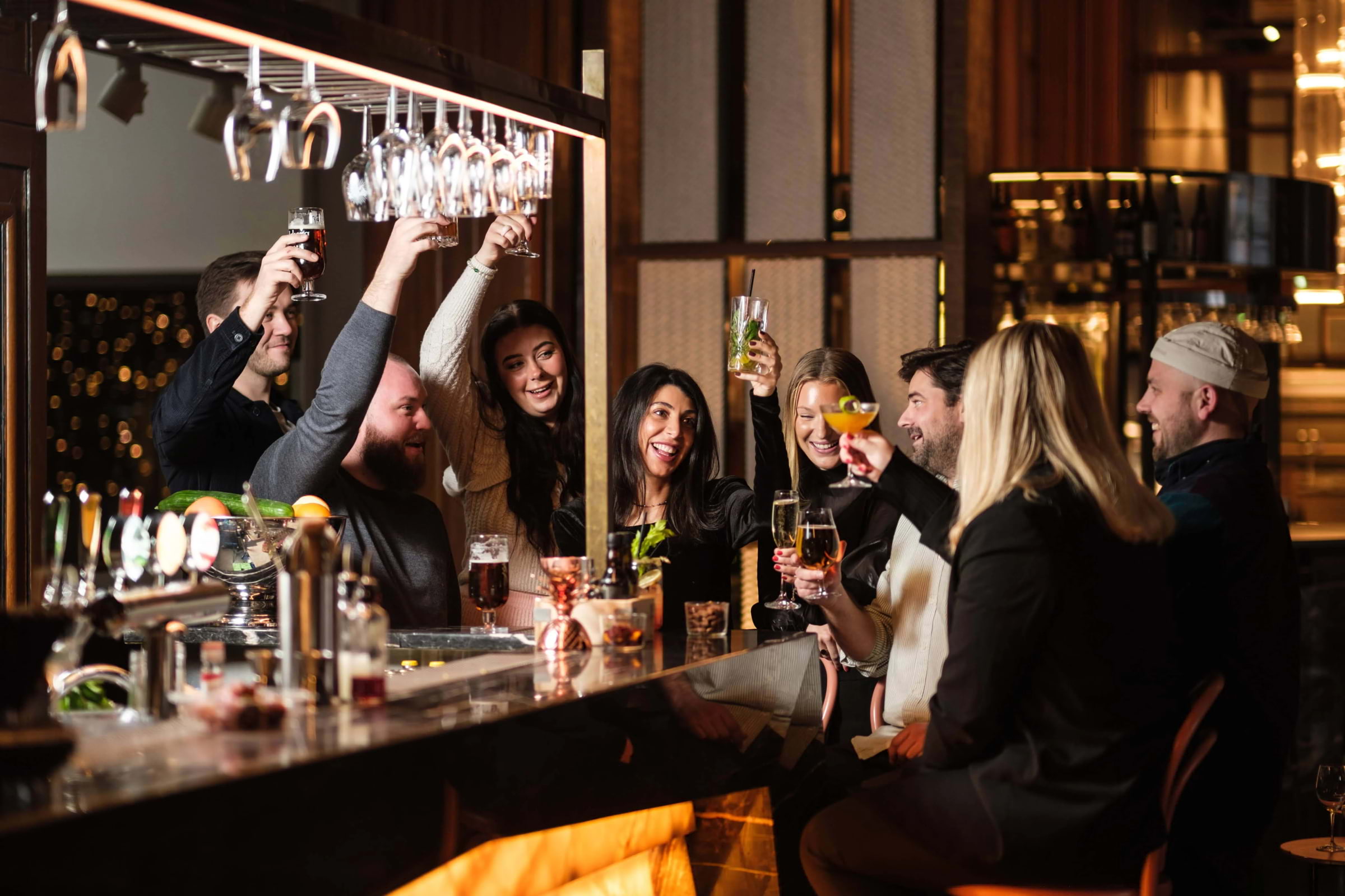 A group of people toasting in a bar at night