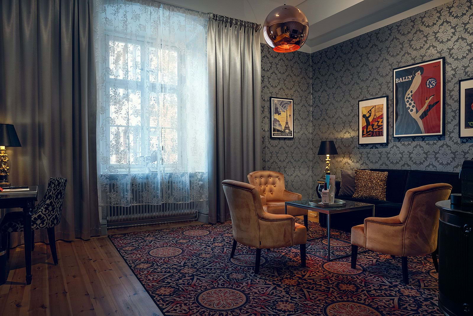 A luxurious seating area in a hotel room with a big window and a patterned carpet