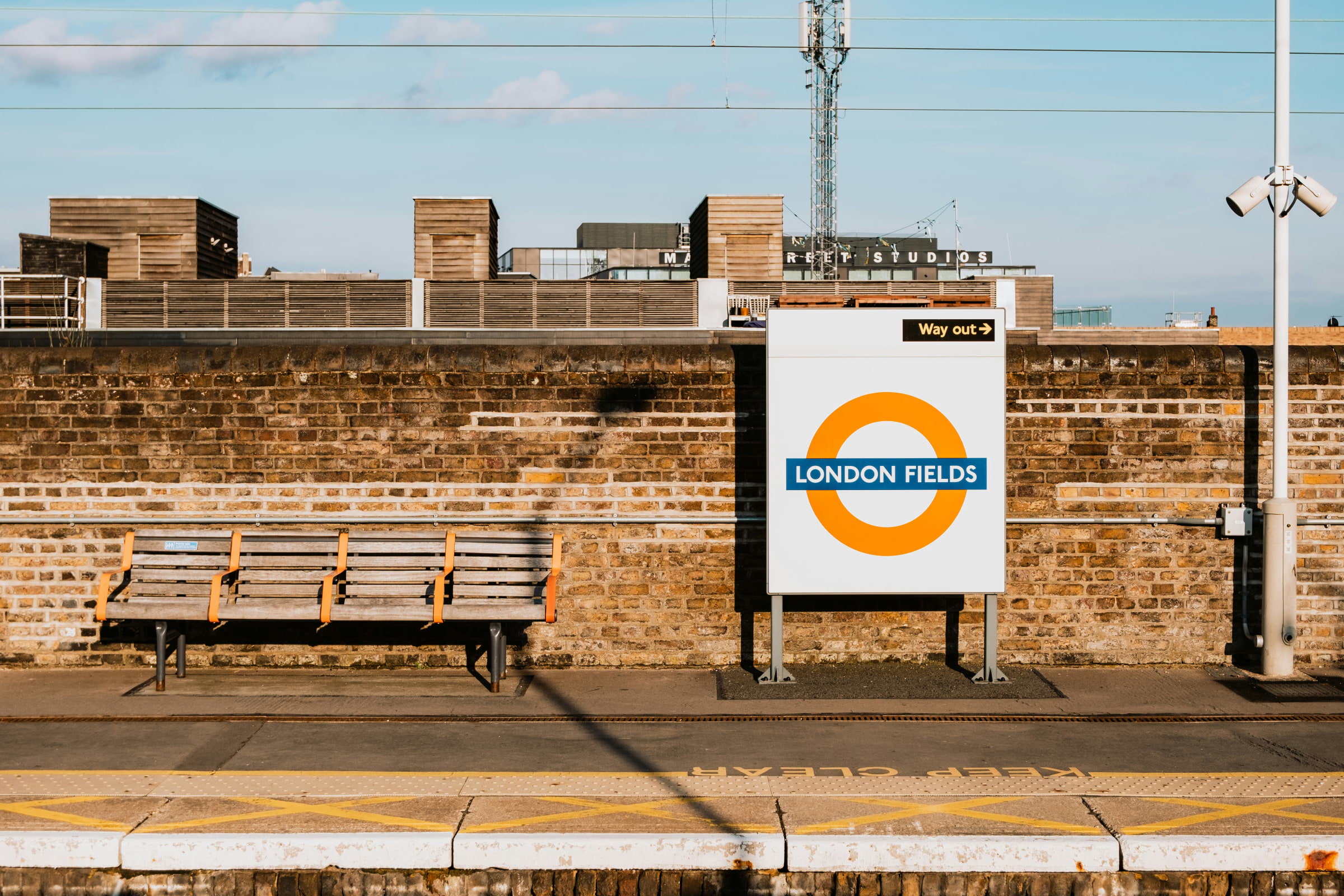 The London Fields tube sign on a train platform next to a wooden bench