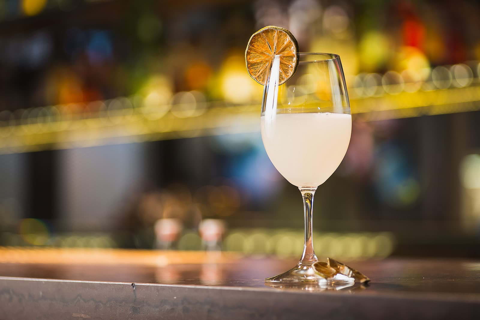 A cocktail with a lime wedge on a bar counter