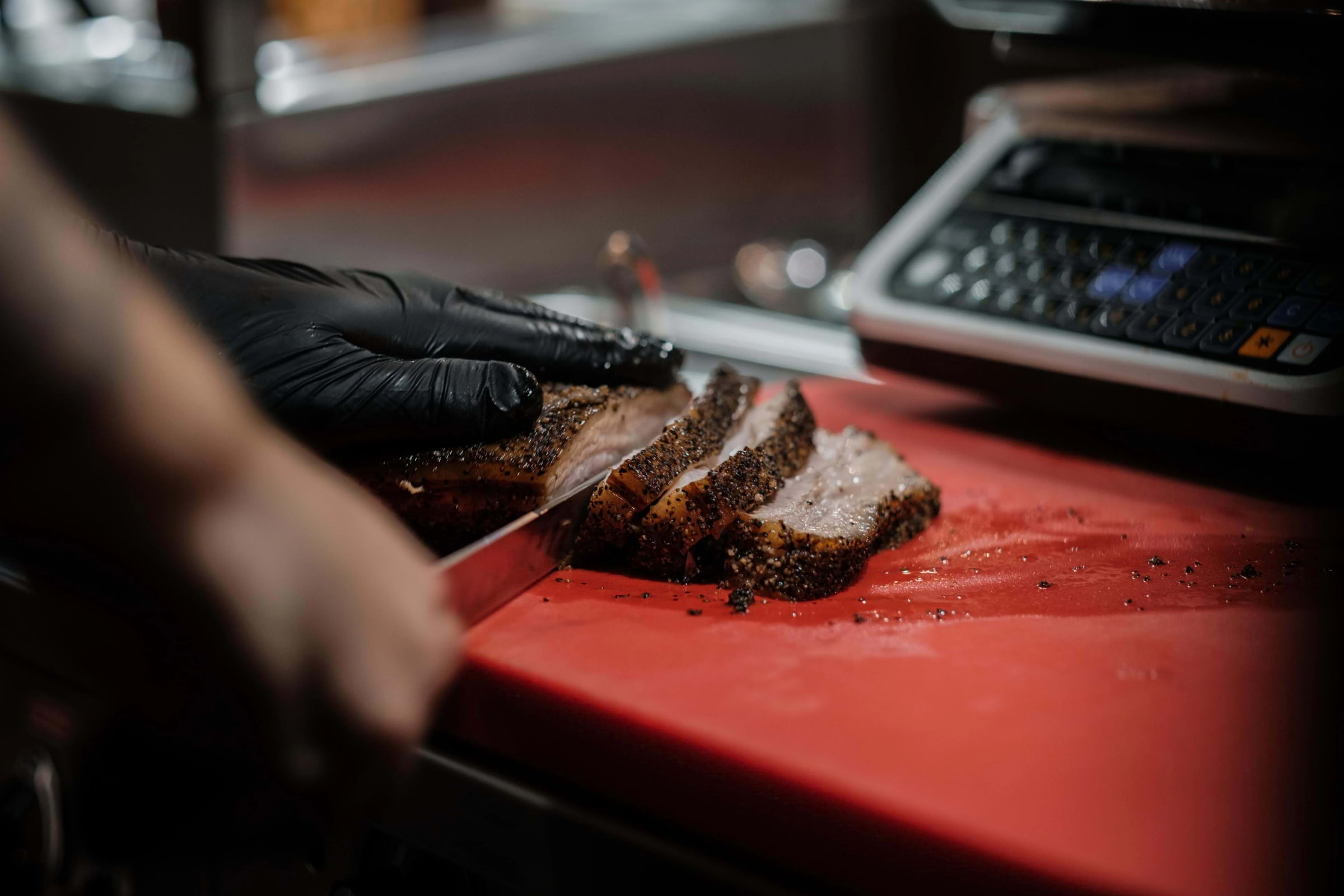 A chef cutting steak on a red cutting board