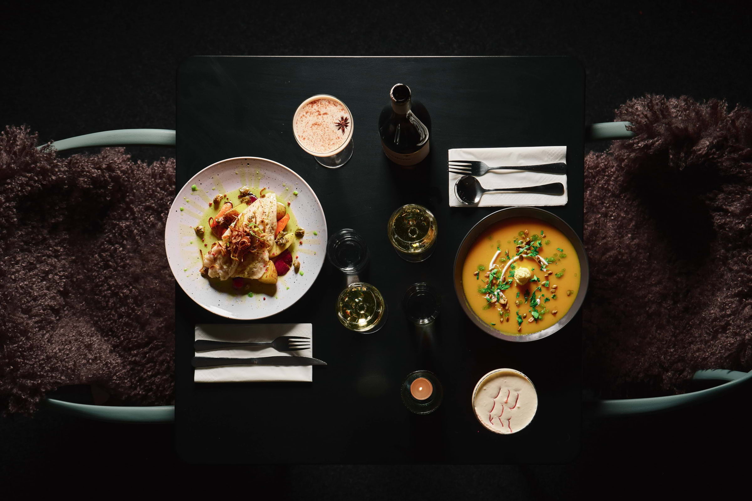 Food and drinks set out on a black table for two in a stylish restaurant