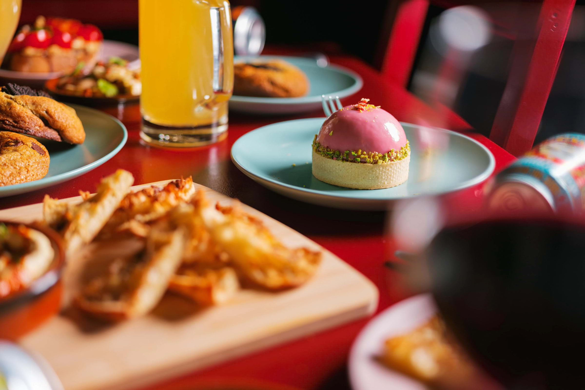 A colourful dessert and other dishes laid out on a red restaurant table