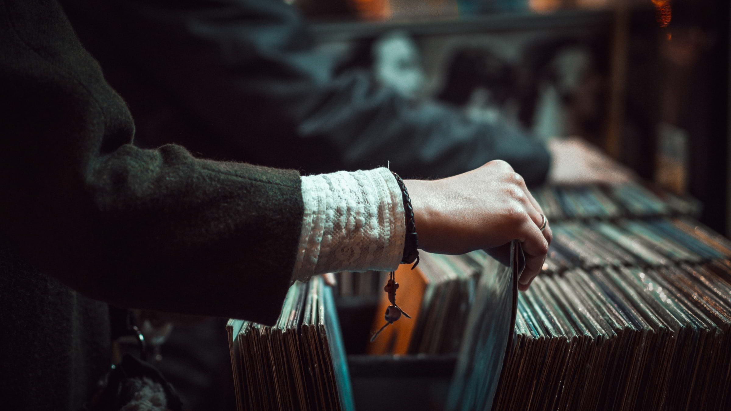 A person's hand rummaging through a box of records