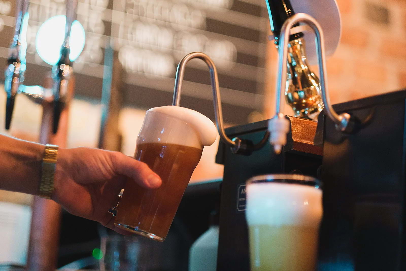 Close-up of a beer with a large head of foam being poured from the tap