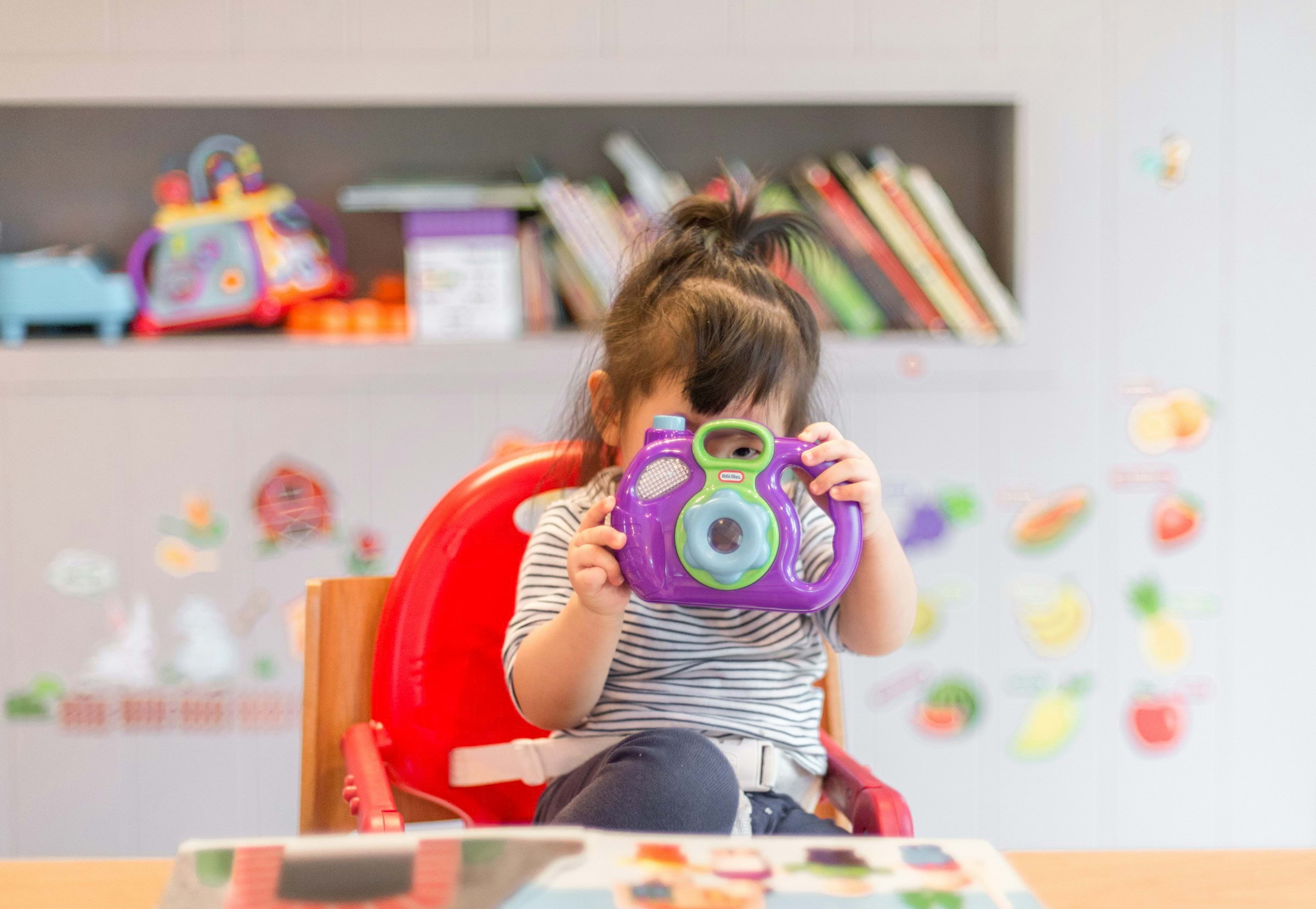 Girl holding purple and green camera toy