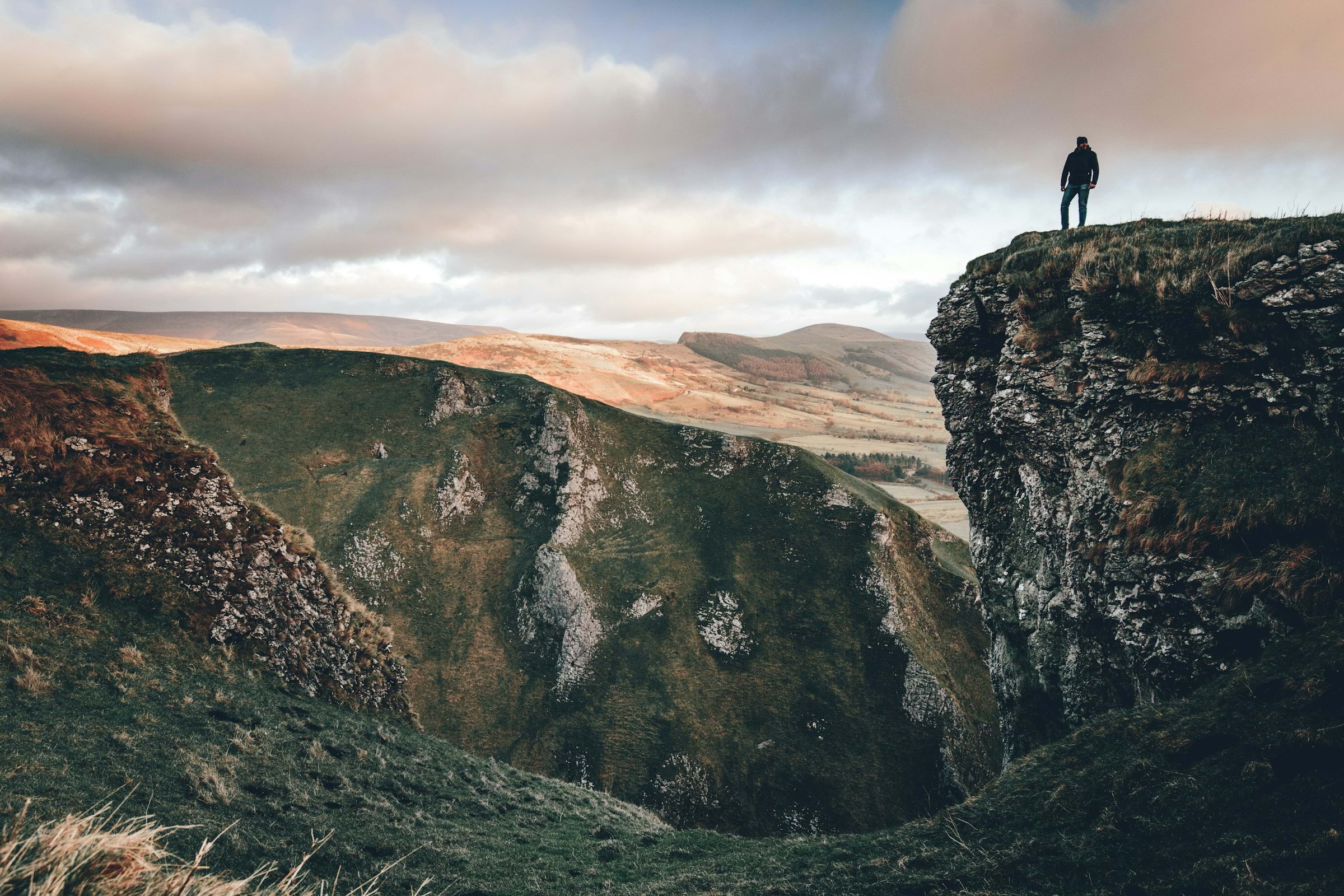 A hiker on a cliff looking out over the Peak District