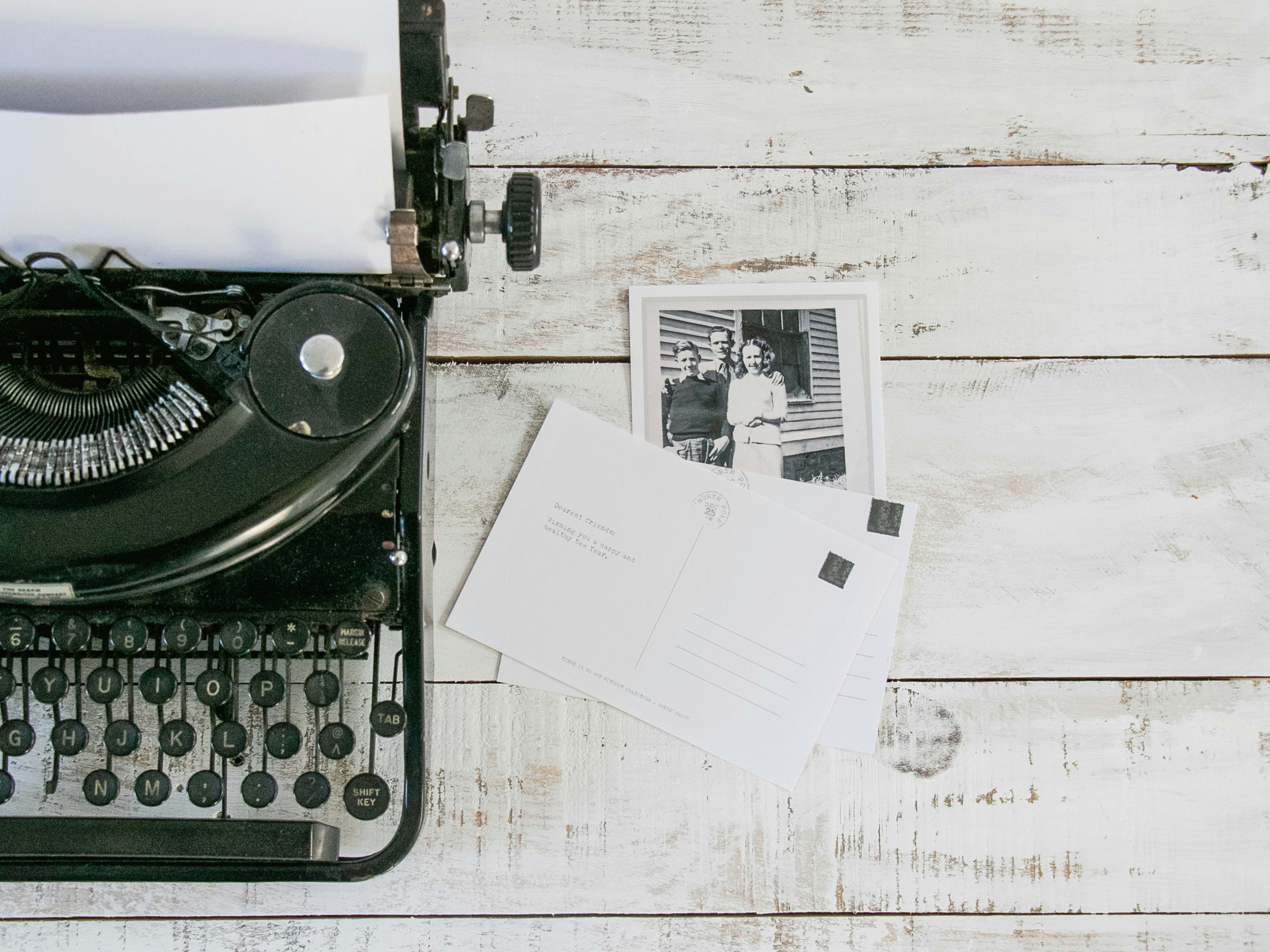 A black and white typewriter with postcards next to it