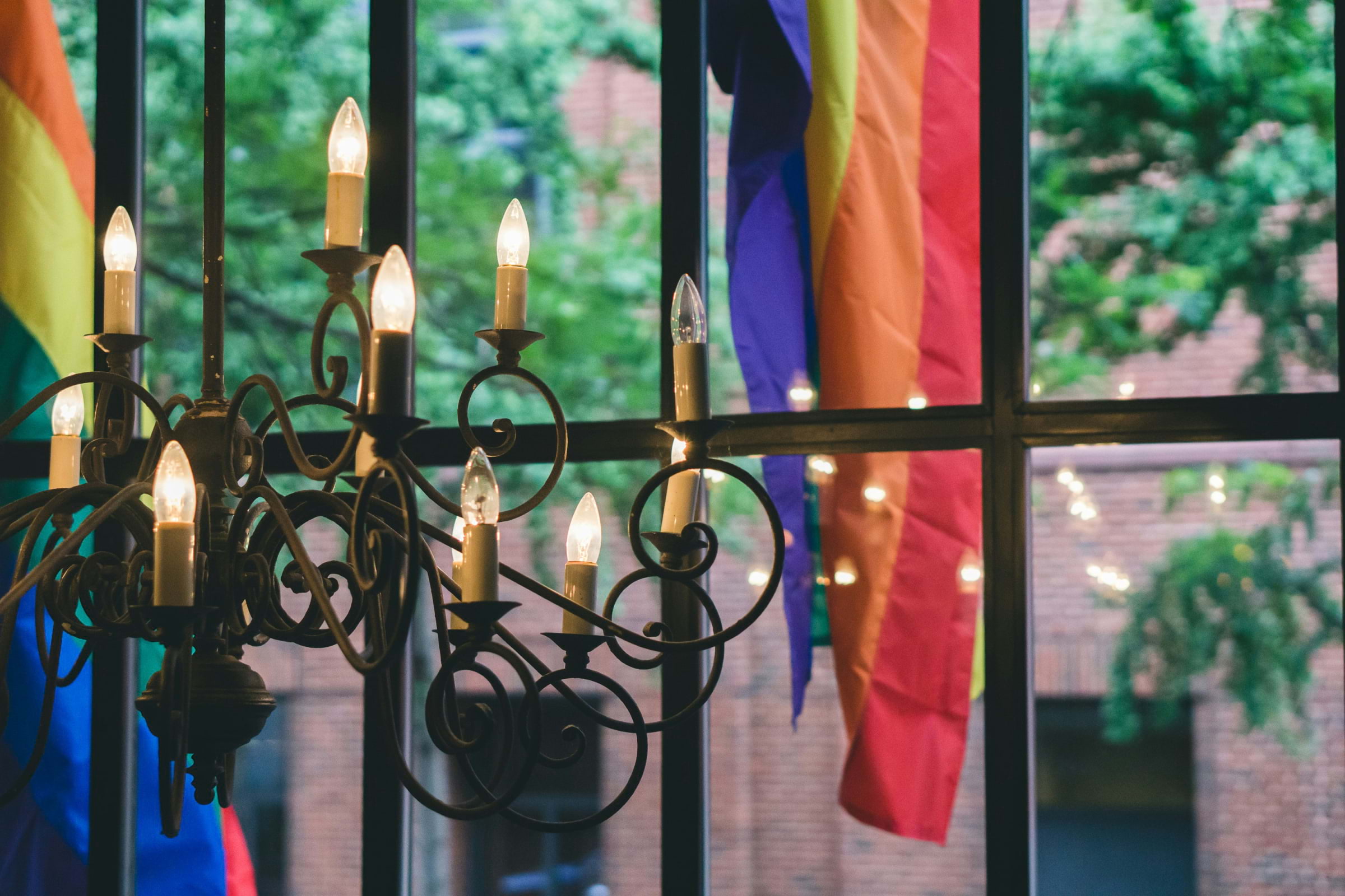 Candles in front of a window with a rainbow flag in the background