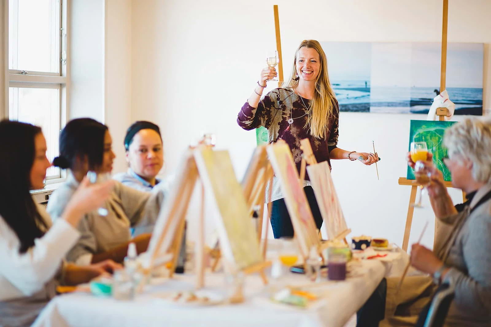 A group of women raising their glasses in a painting workshop