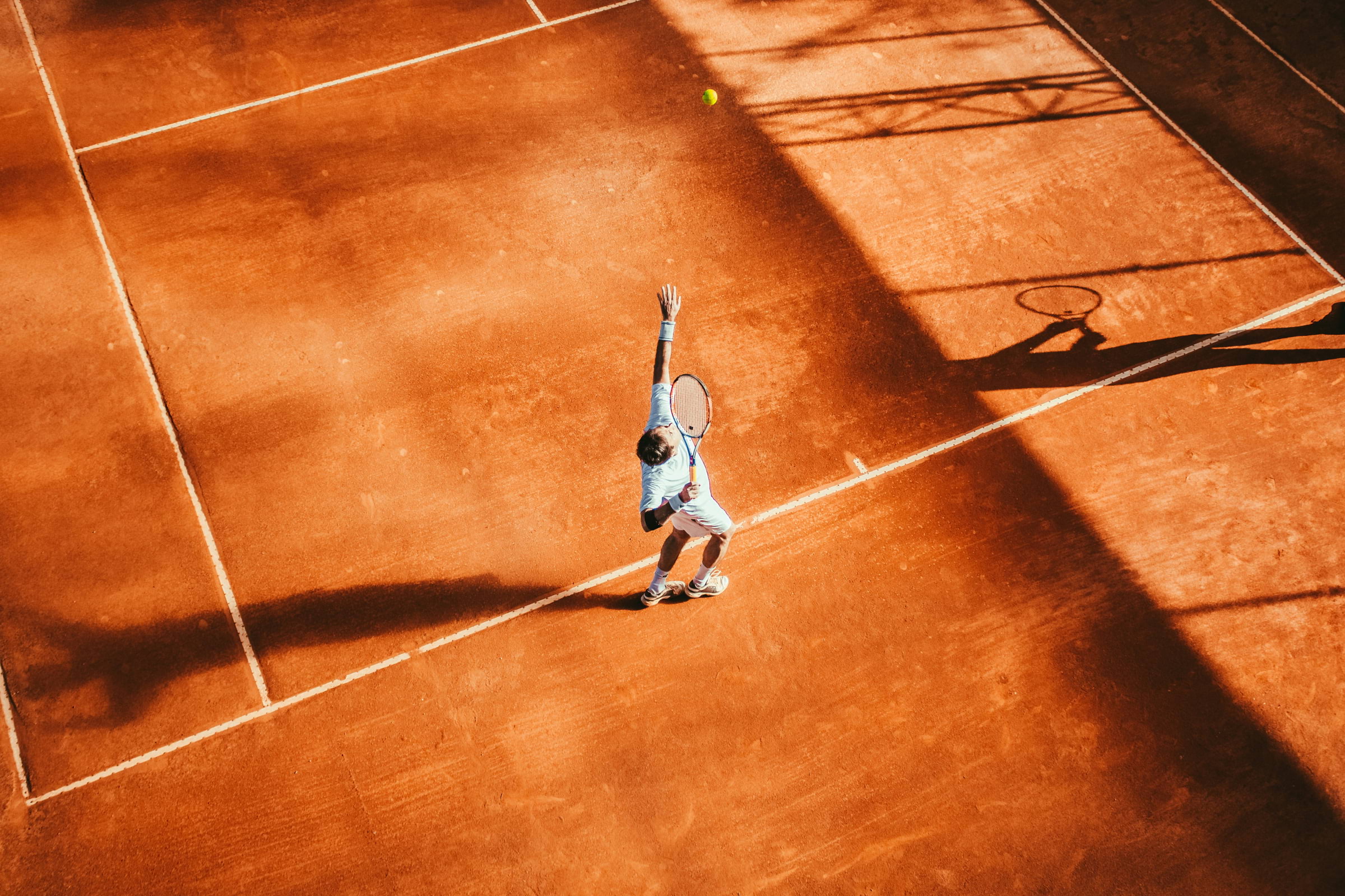 A man on a tennis court about to hit a ball with a tennis racket