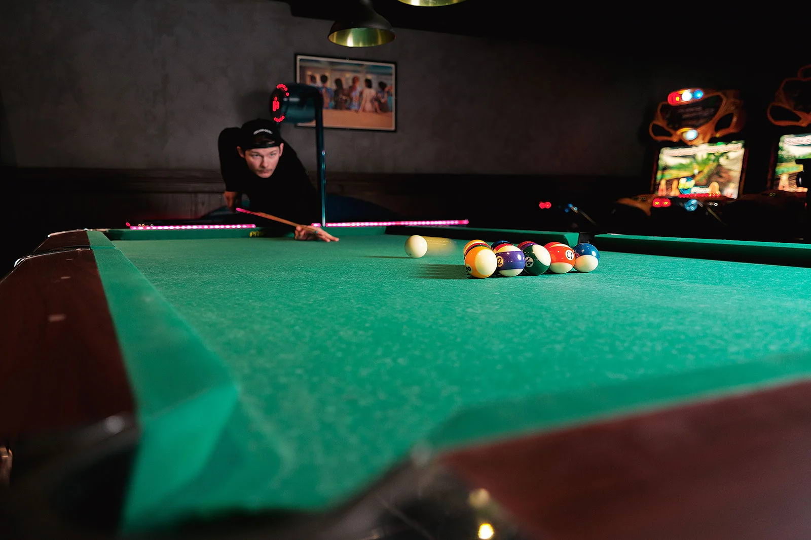 A pool player breaking a rack on a pool table in a bar