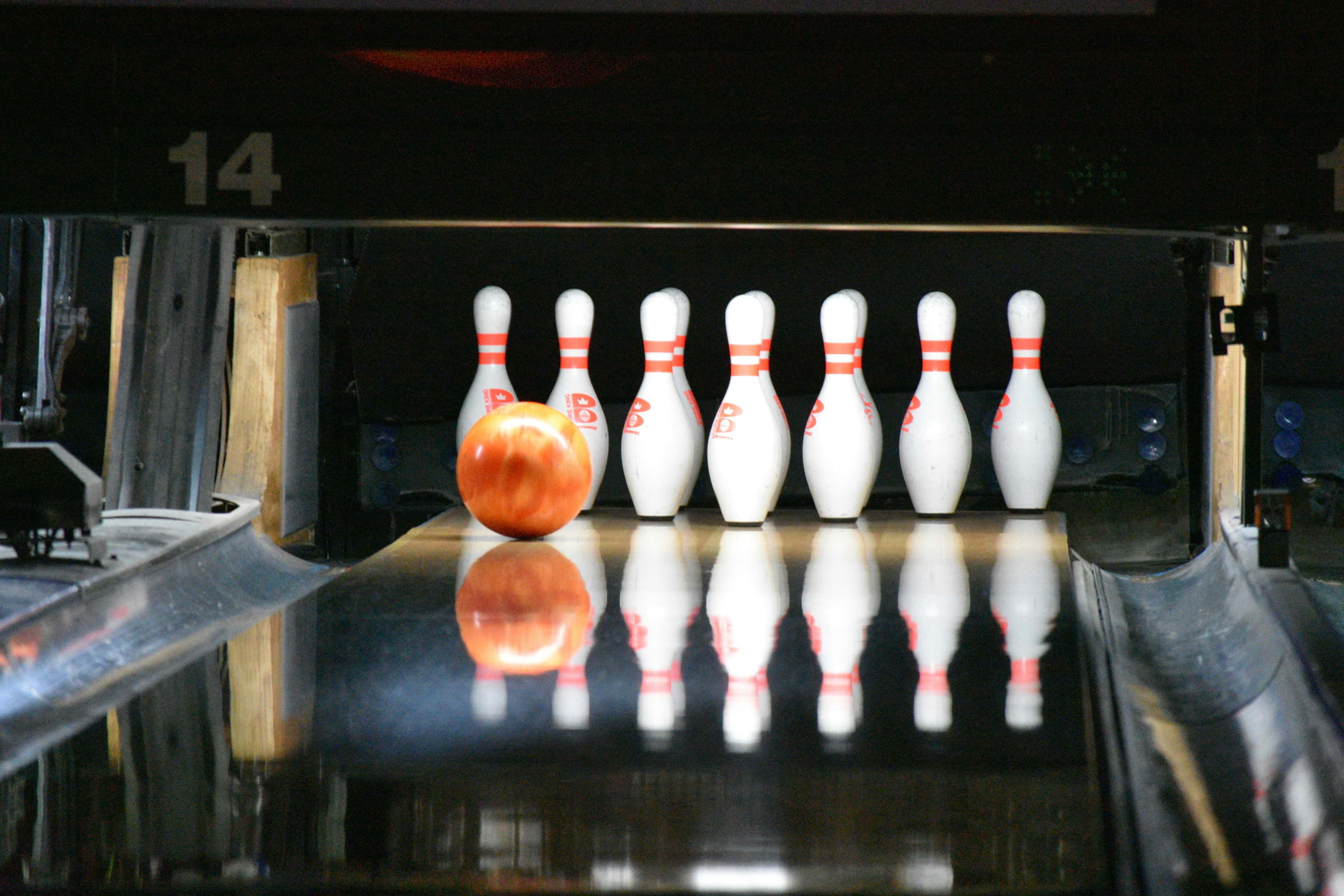 A bowling ball rolling towards pins on a bowling lane