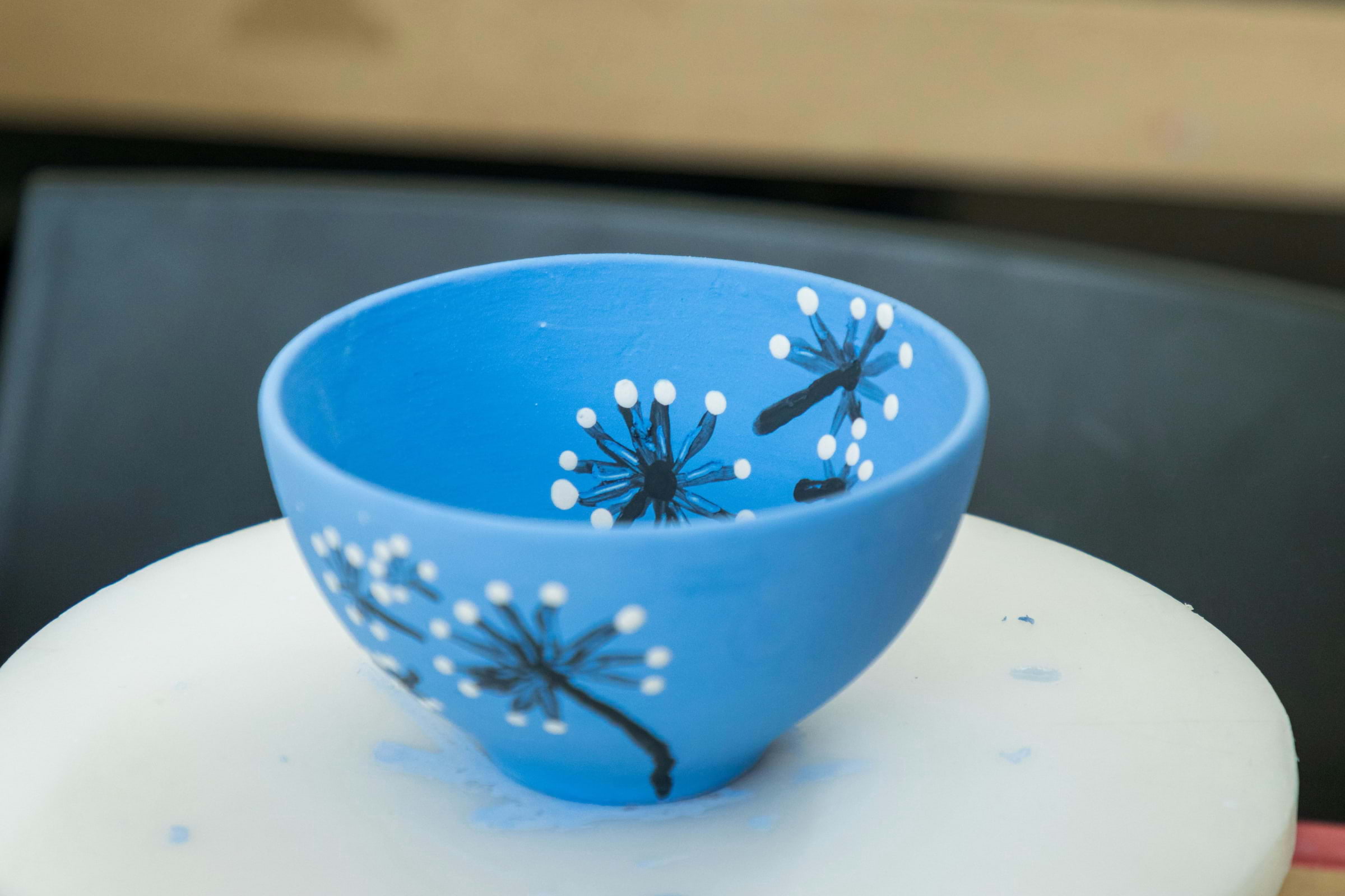 A blue ceramic bowl with dandelions painted on it