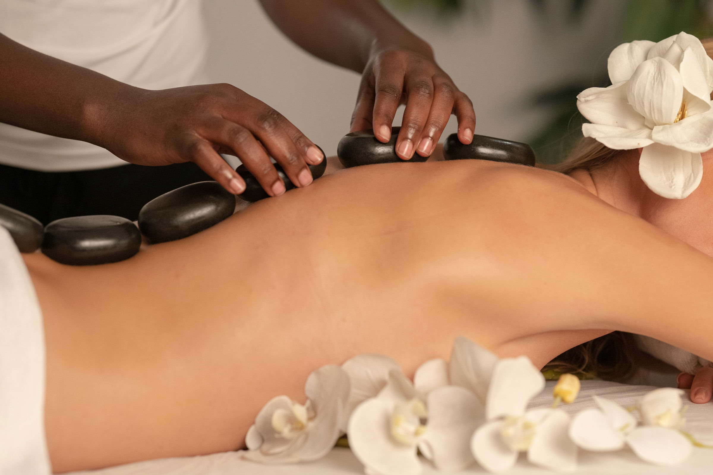 A massage therapist placing hot stones on a client's back