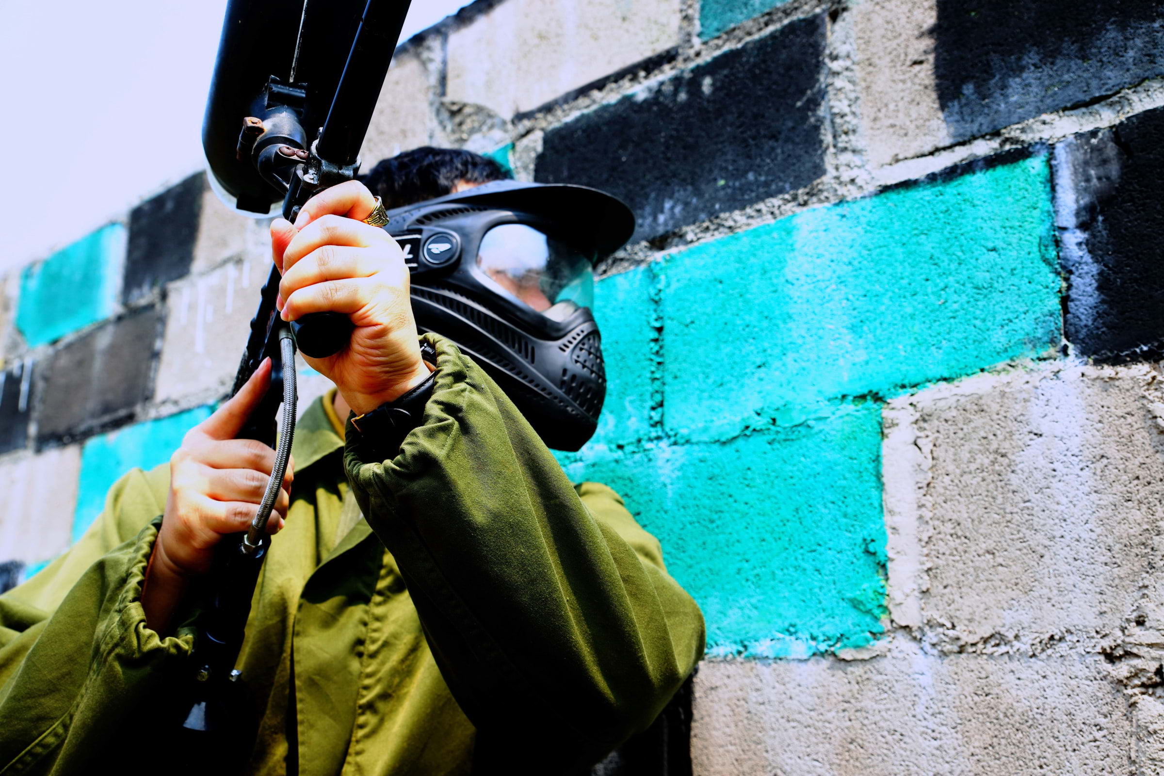 A paintball player hiding behind a painted concrete wall