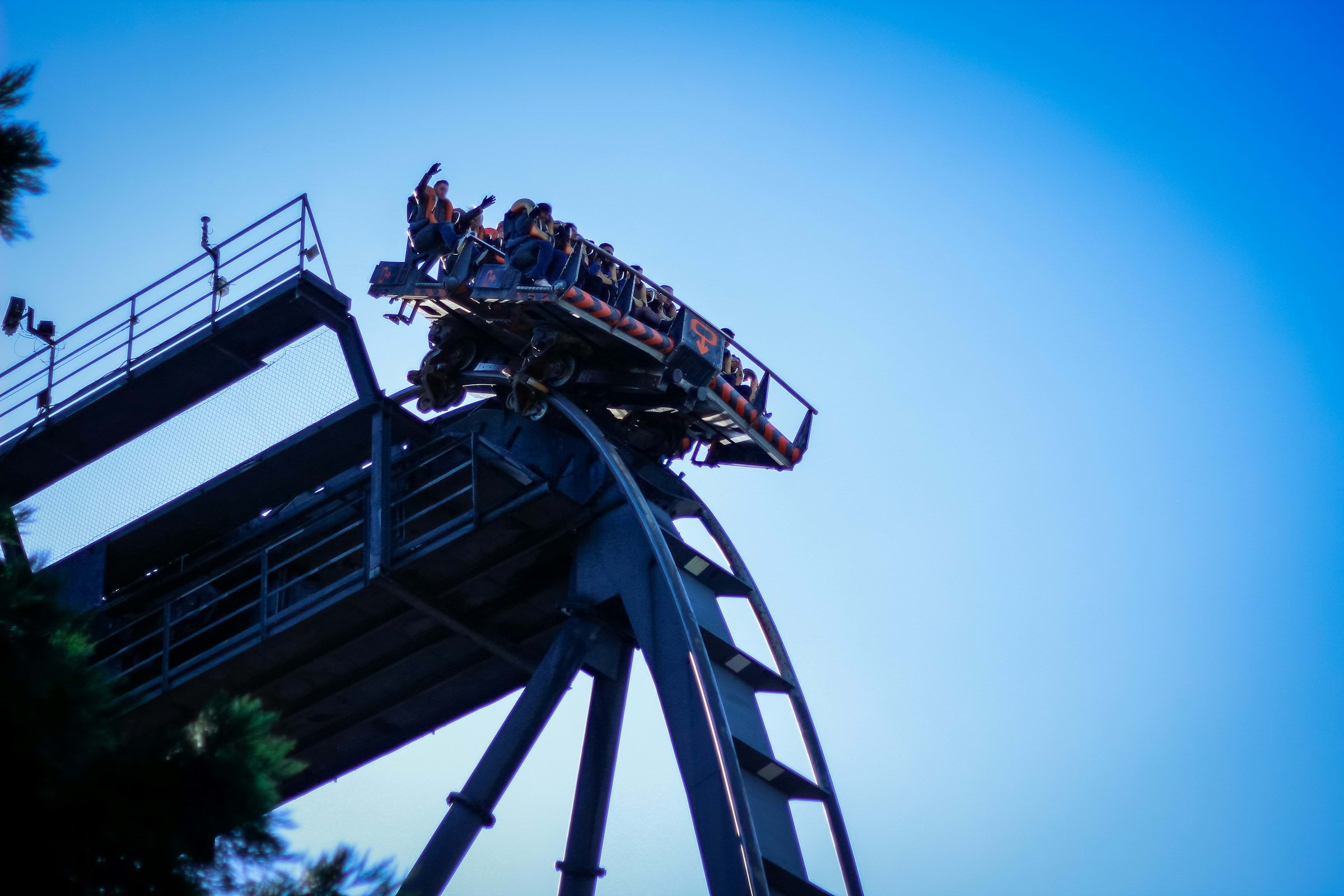 A rollercoaster cart about to plunge, with a clear blue sky backdrop