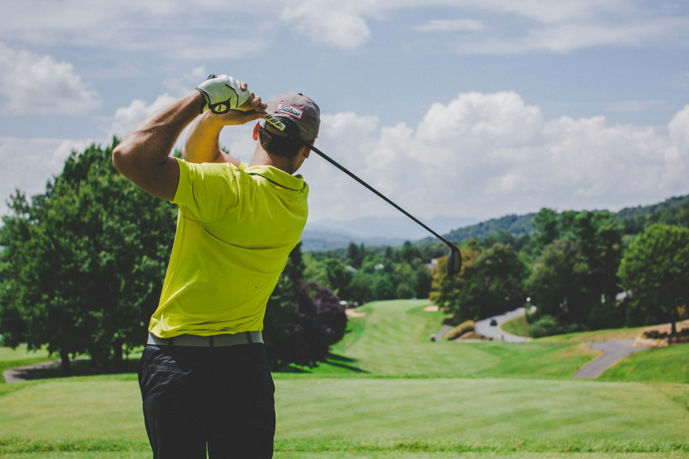 A golfer in a green shirt hitting a golf ball into the distance