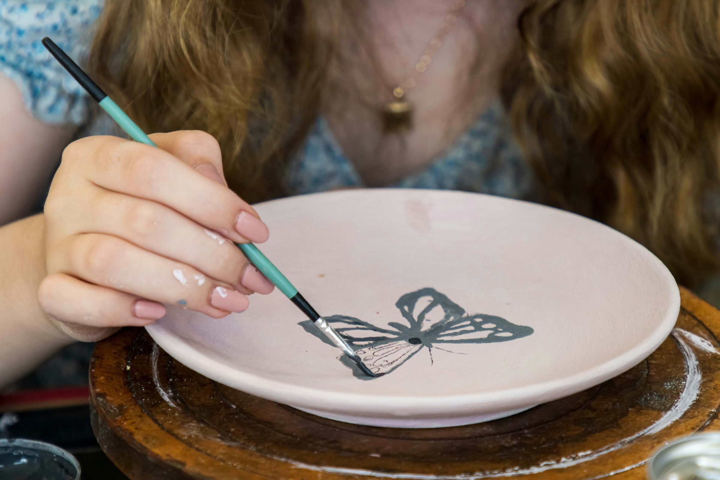 A woman painting a piece of pottery