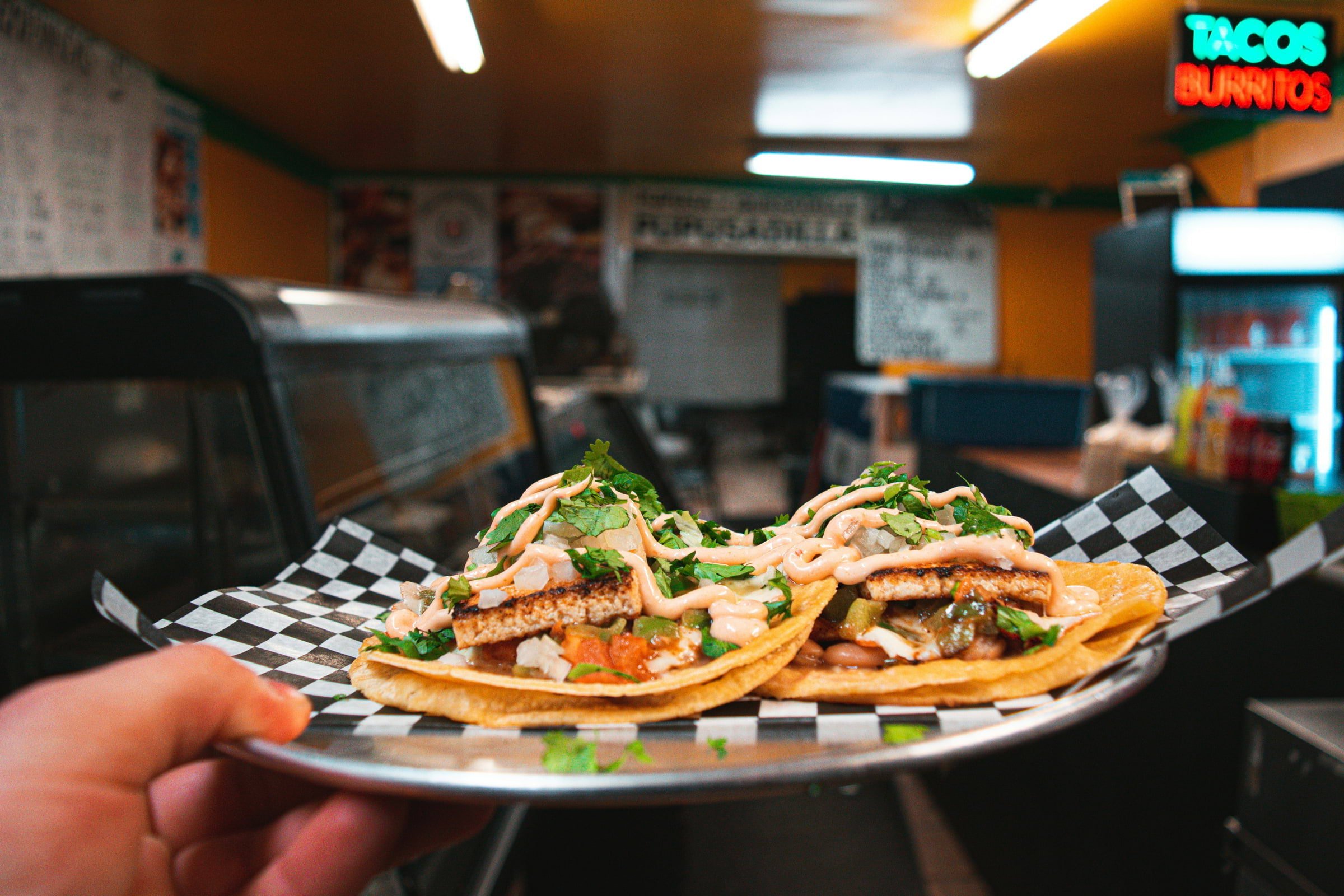 A plate of two tacos being held up