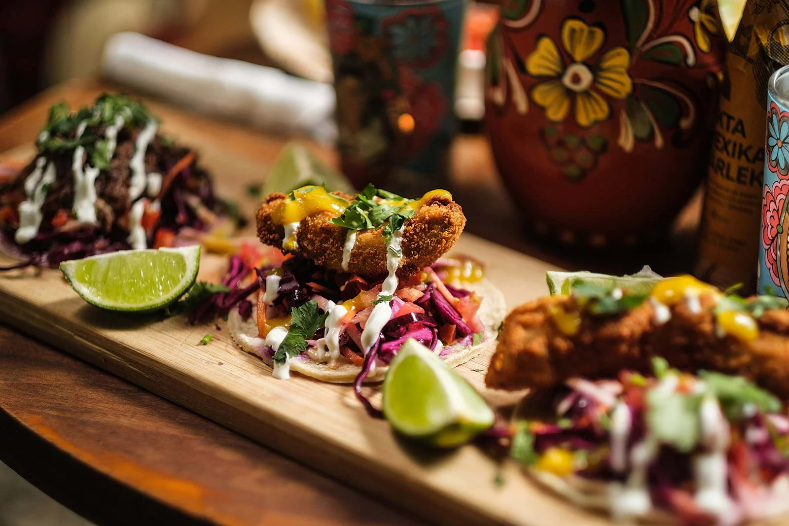 Three tacos on a wooden board in Mexican restaurant