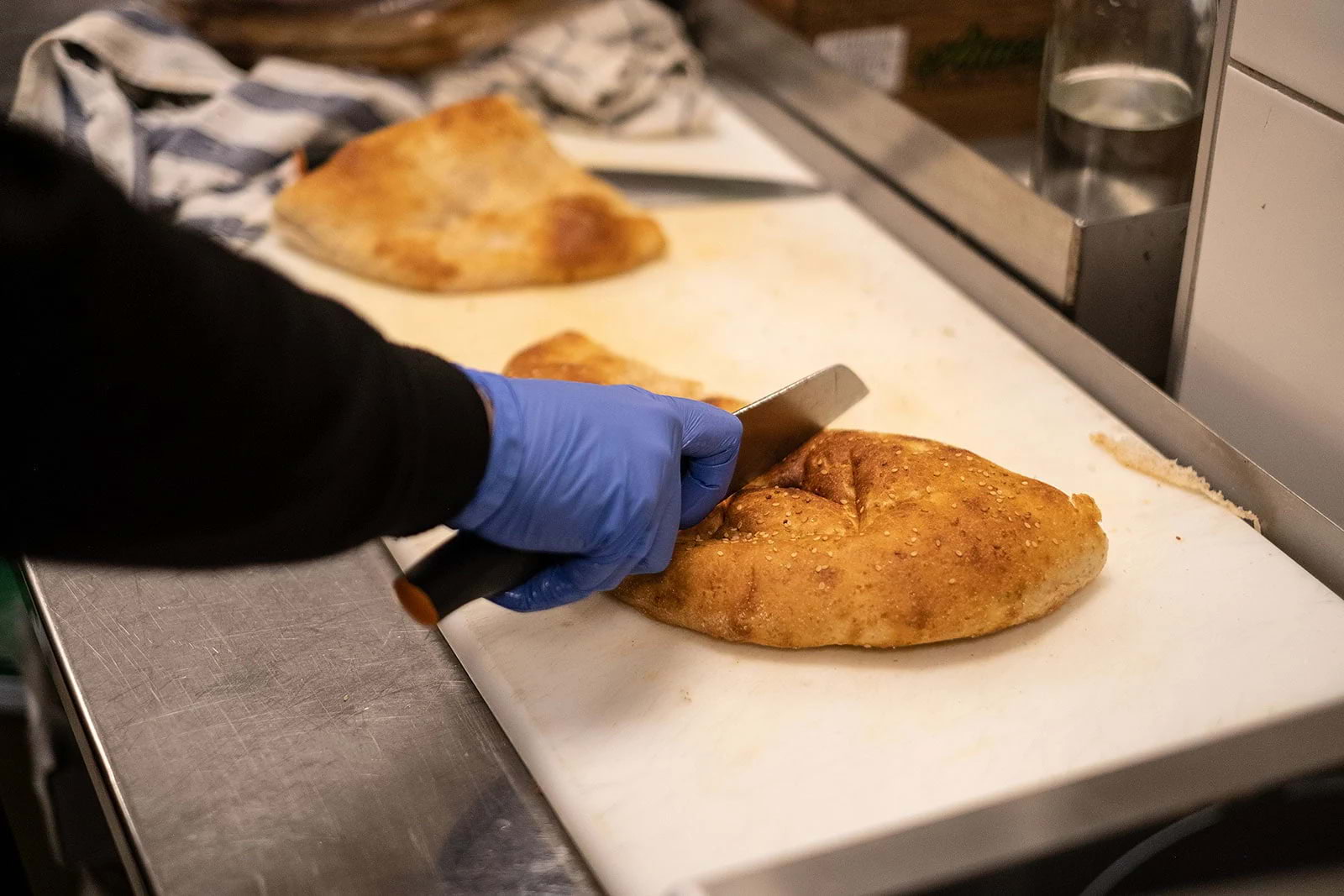 A chef cutting a Turkish flatbread in half