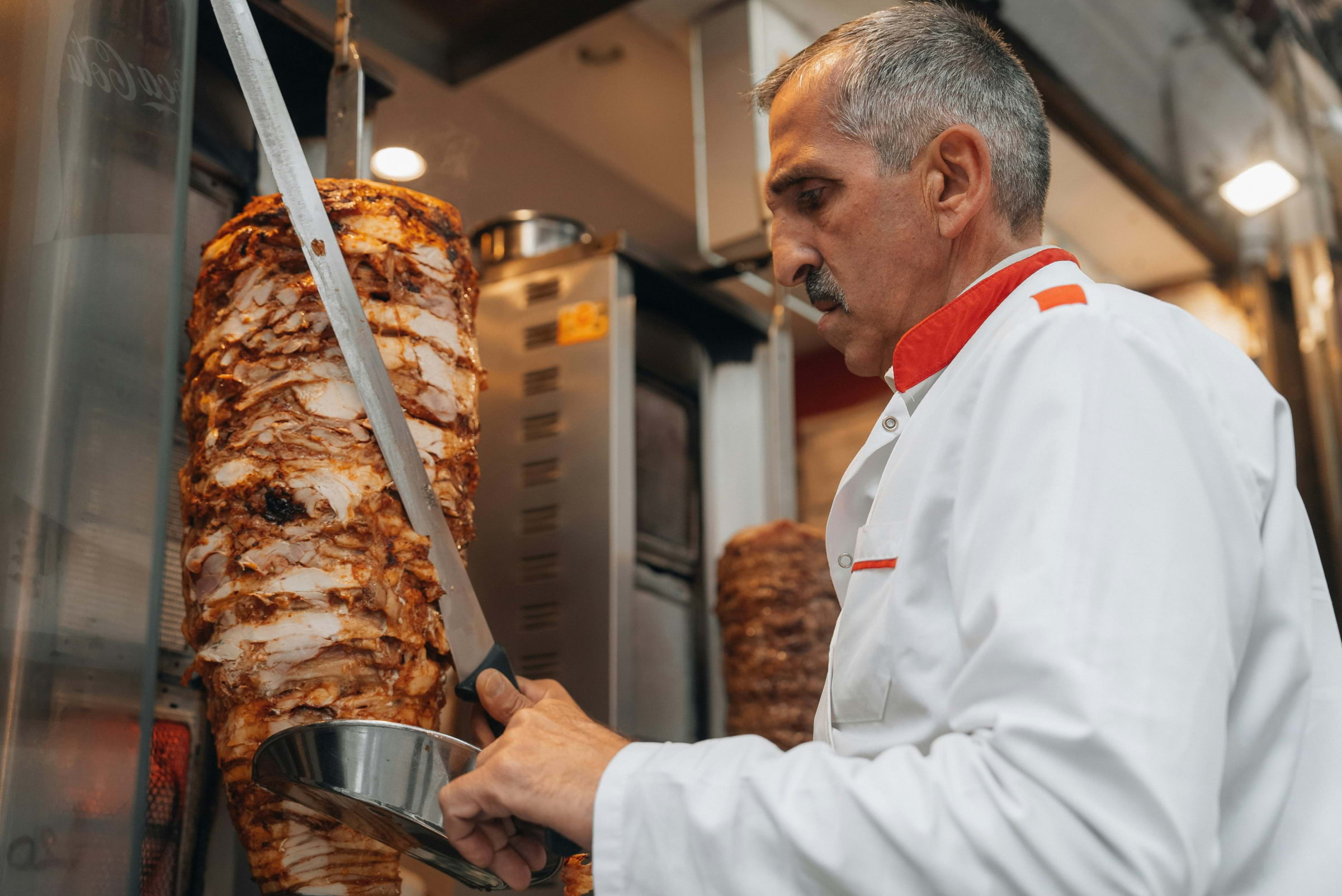 A Turkish man slicing a meat kebab