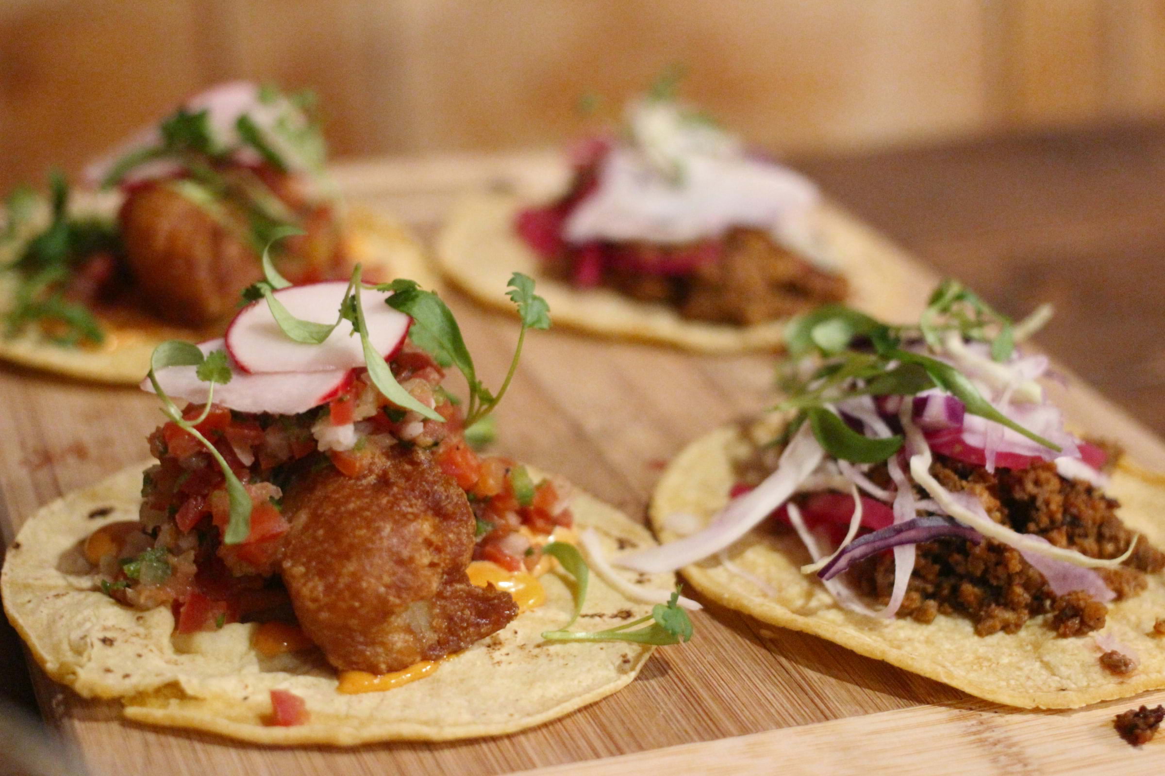 Four tacos with meat, salad, red onions and radishes