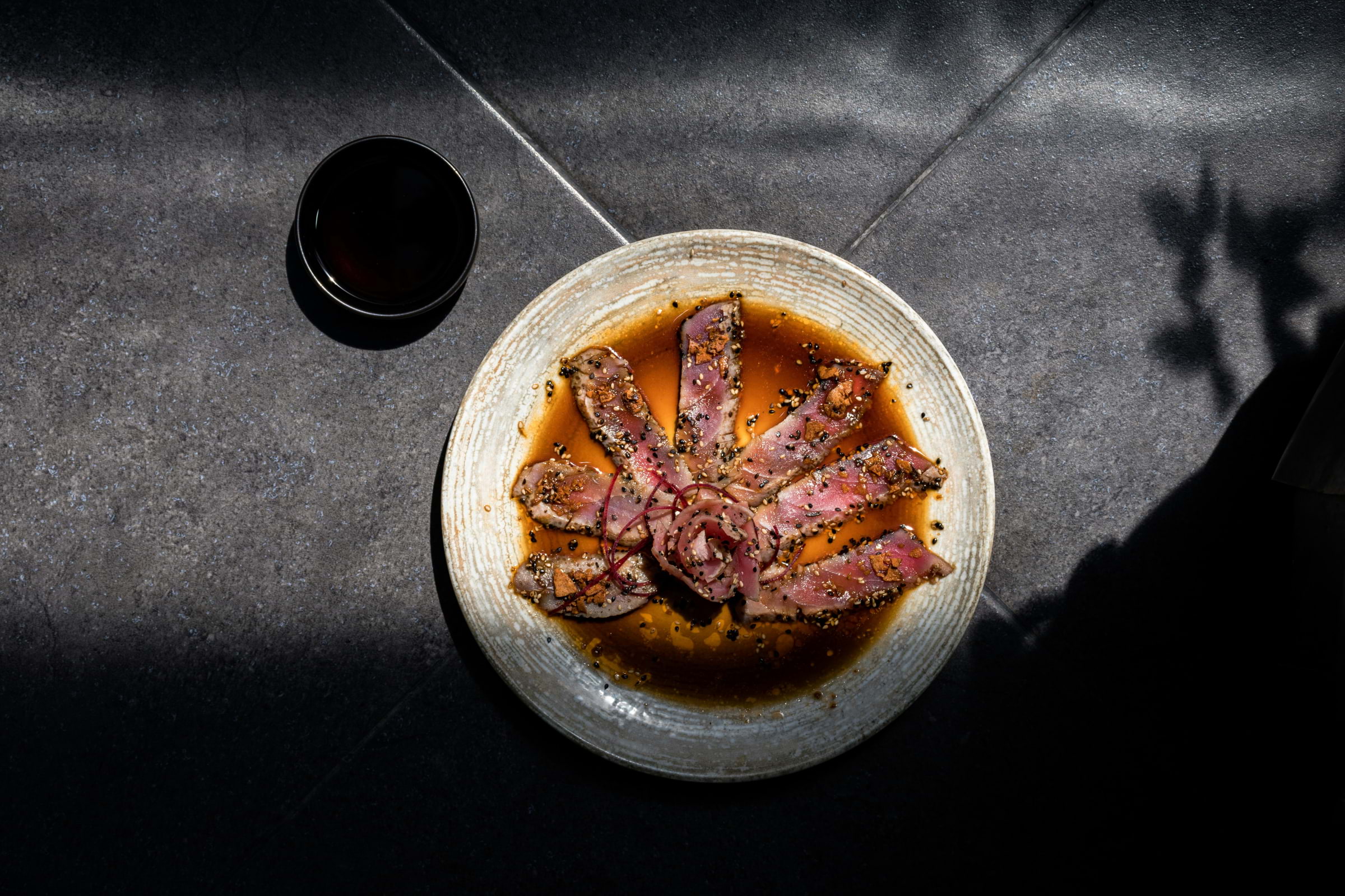 Sushi on a plate with brown sauce and a grey background