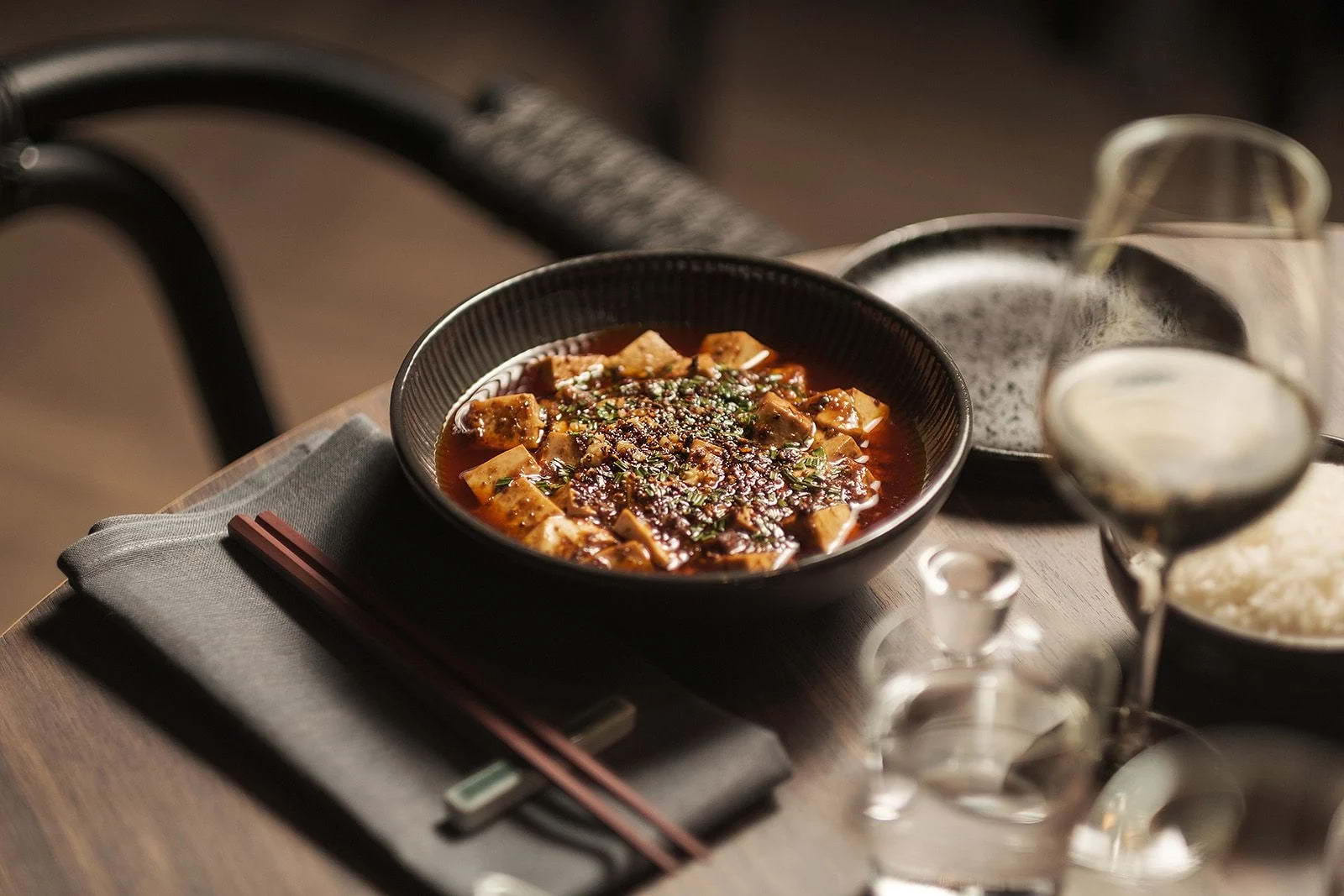 A black bowl of mapo tofu set out on a table in a Chinese restaurant