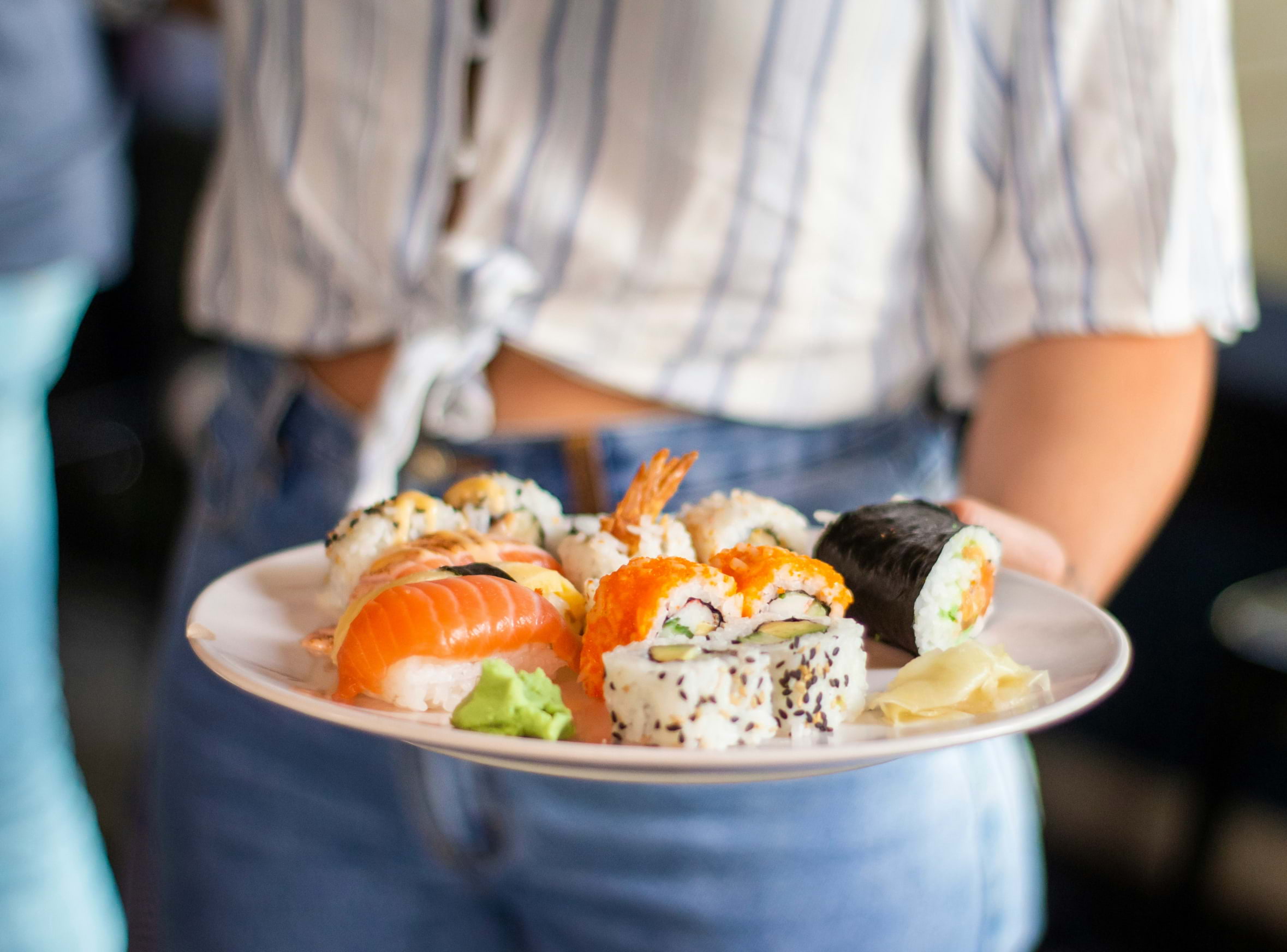 A person holding a plate of sushi