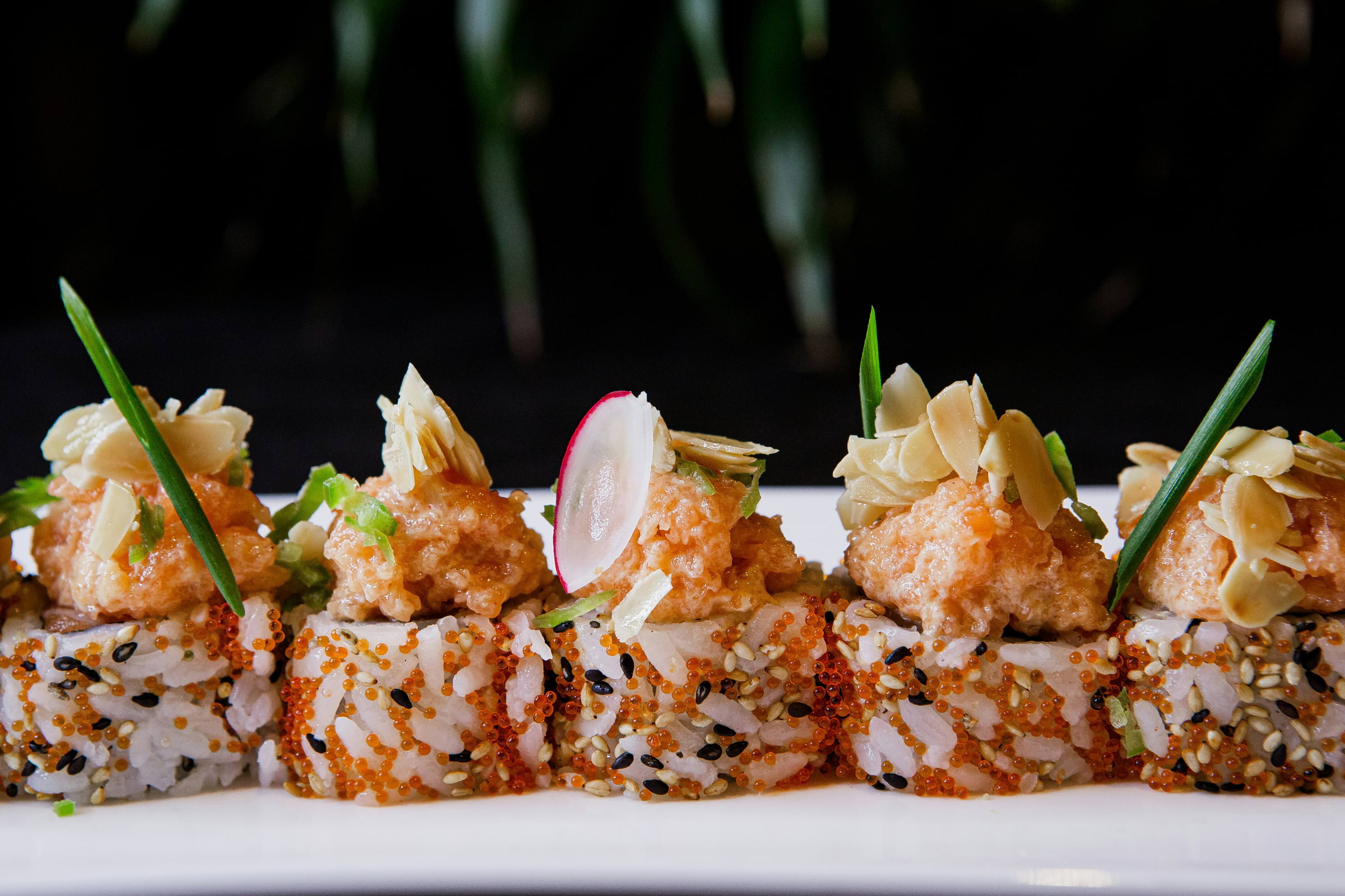 A plate of sushi pieces topped with radish