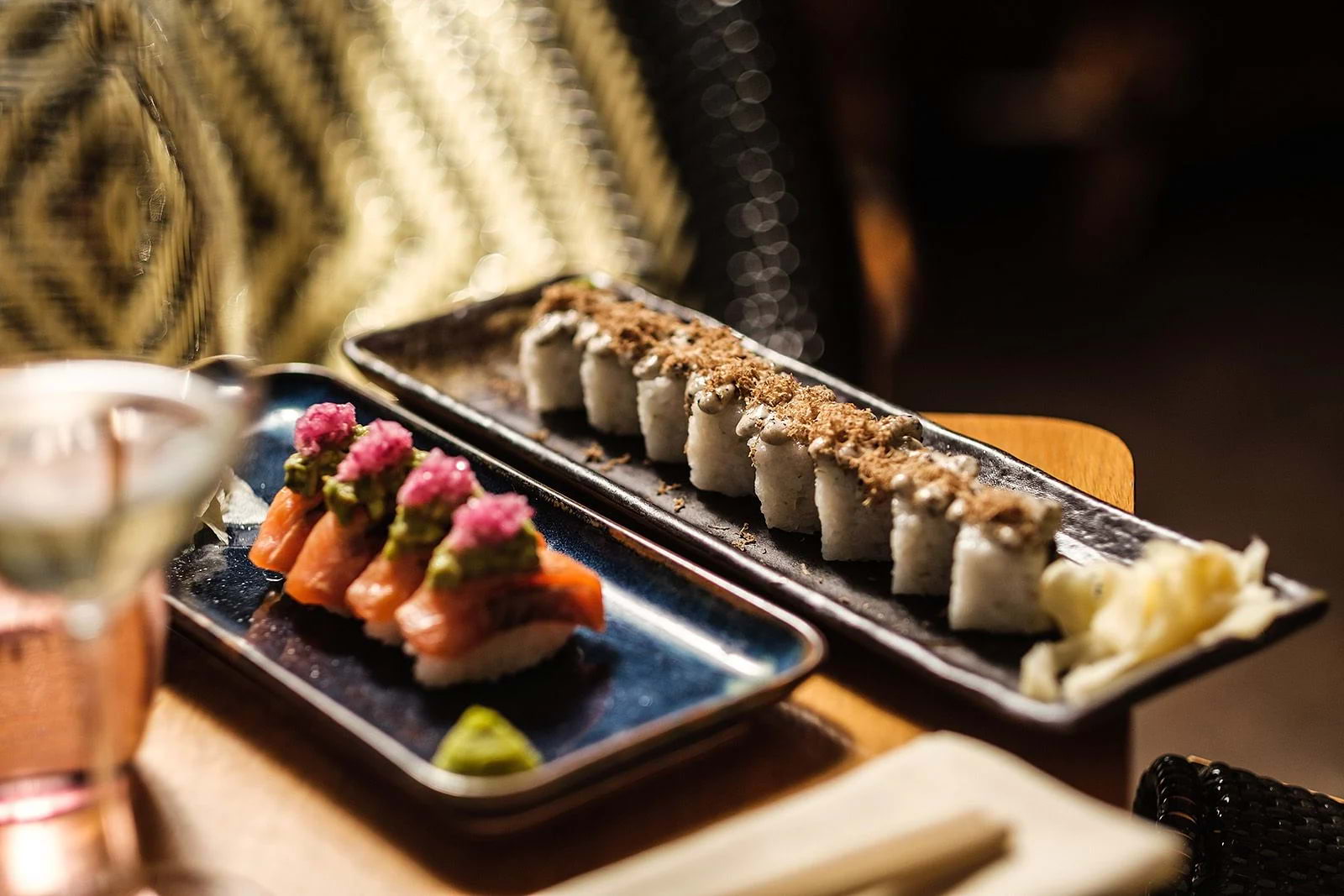 Two plates of sushi set side by side on a restaurant table