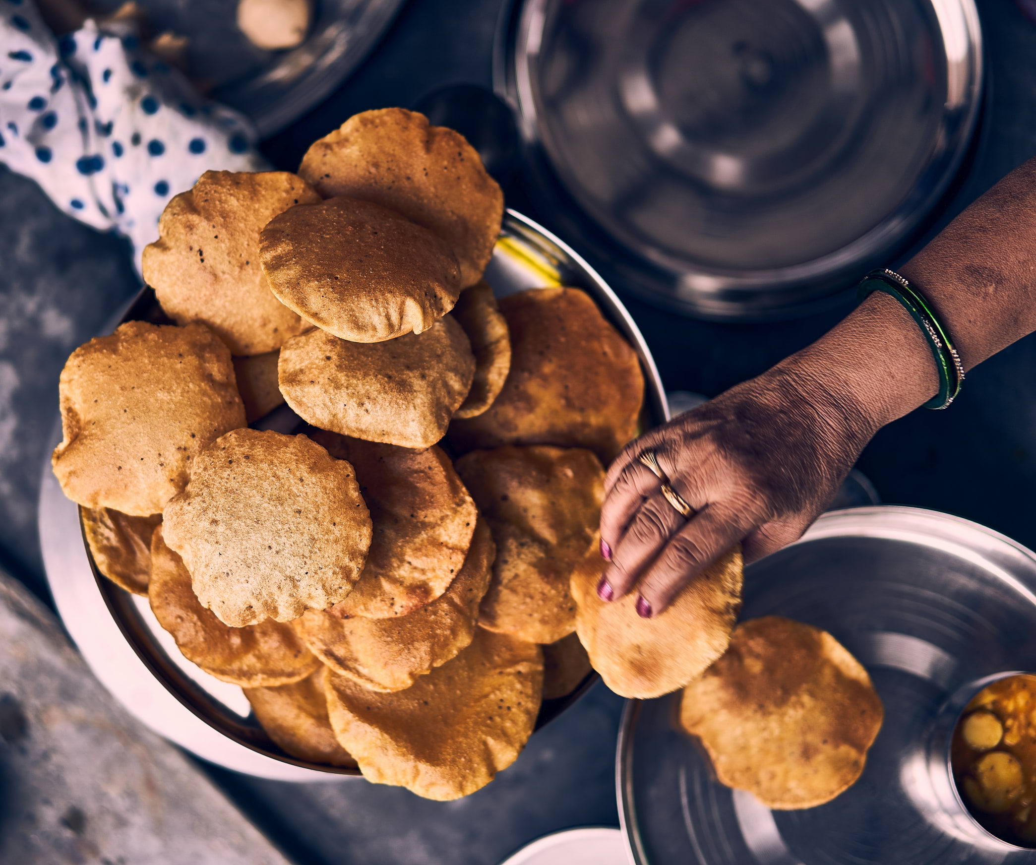 A pile of hot roti being taken off a big plate onto a smaller one