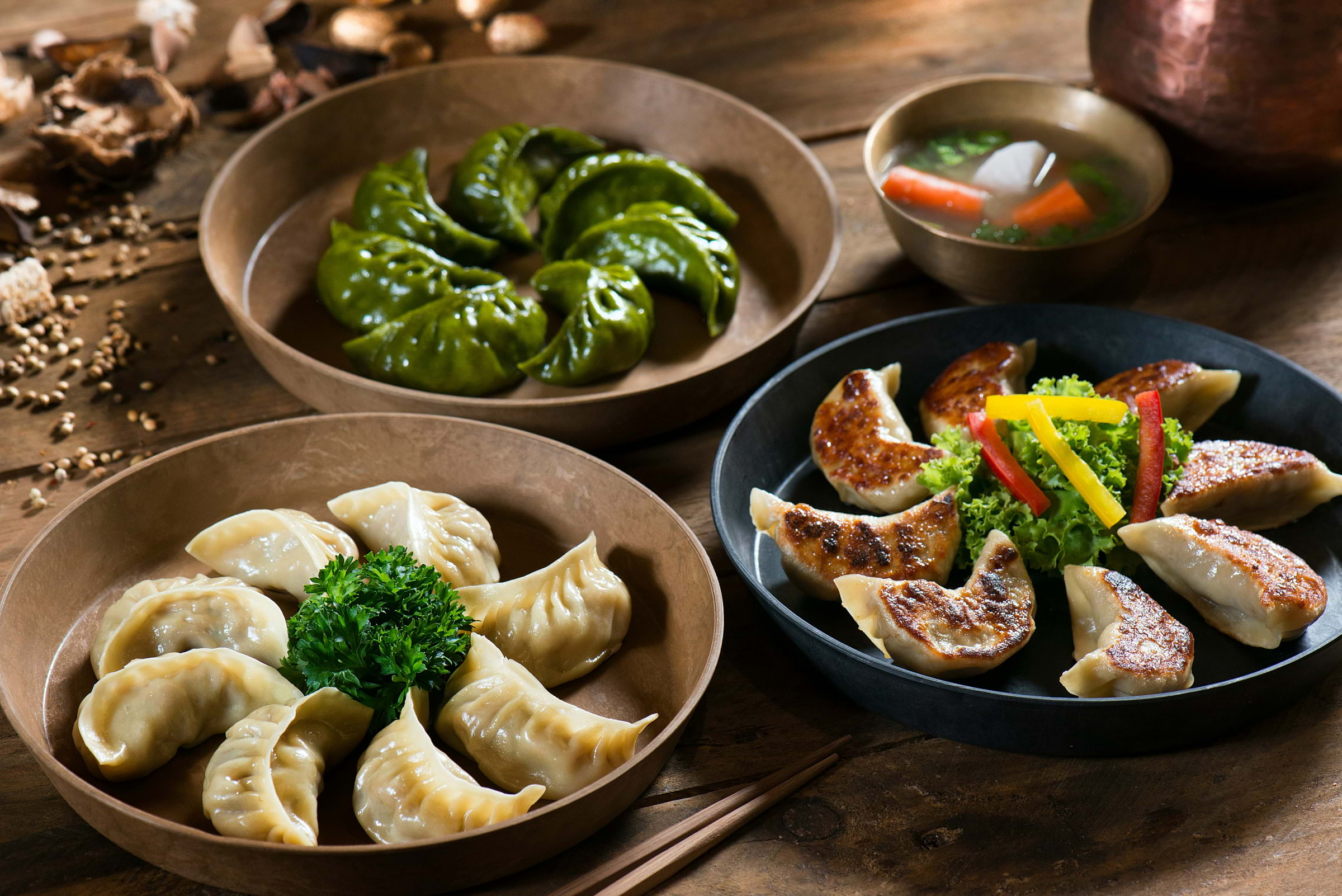 Three bowls of dumplings with vegetables