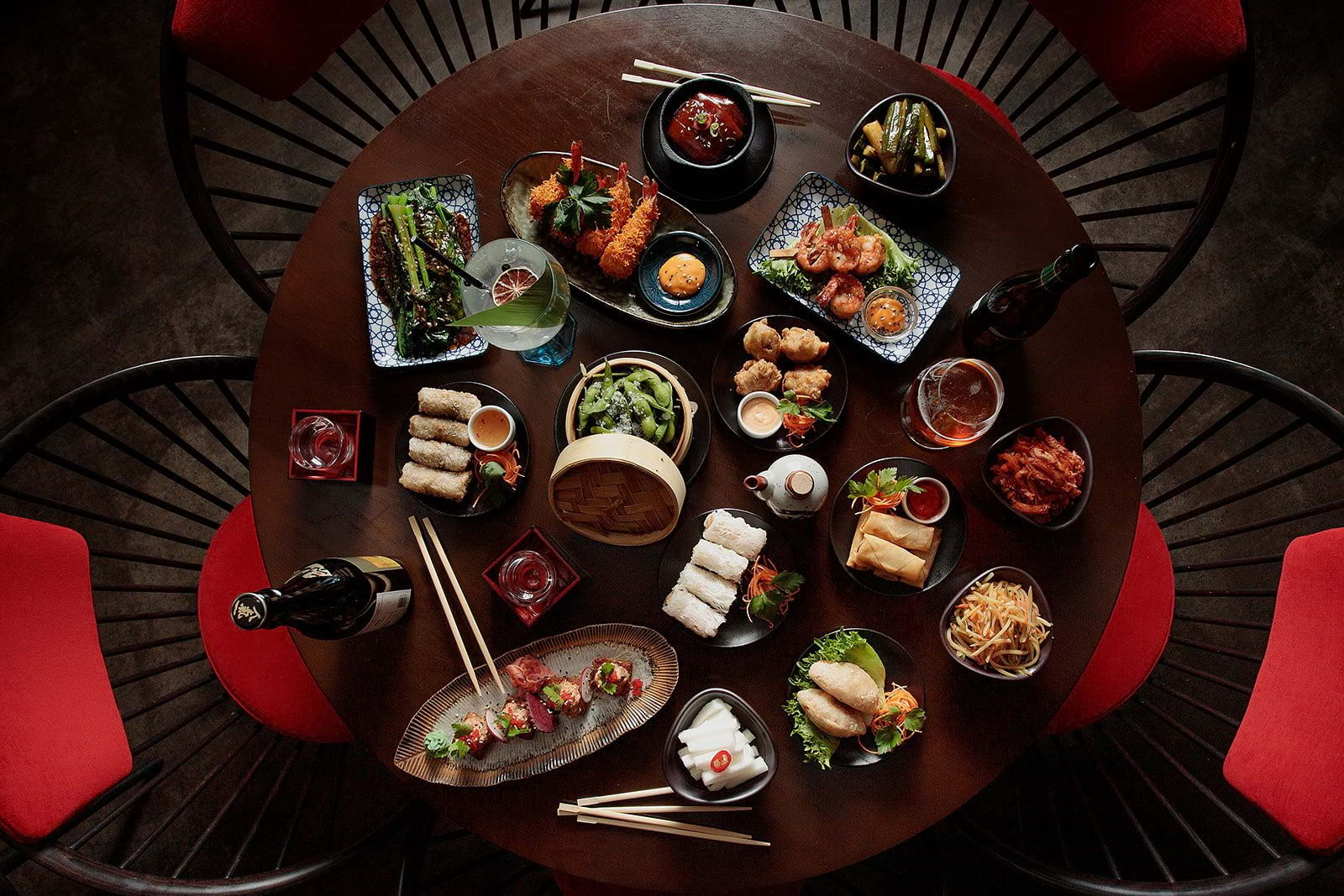 A birds-eye view of a round restaurant table covered with an assortment of Chinese dishes and drinks