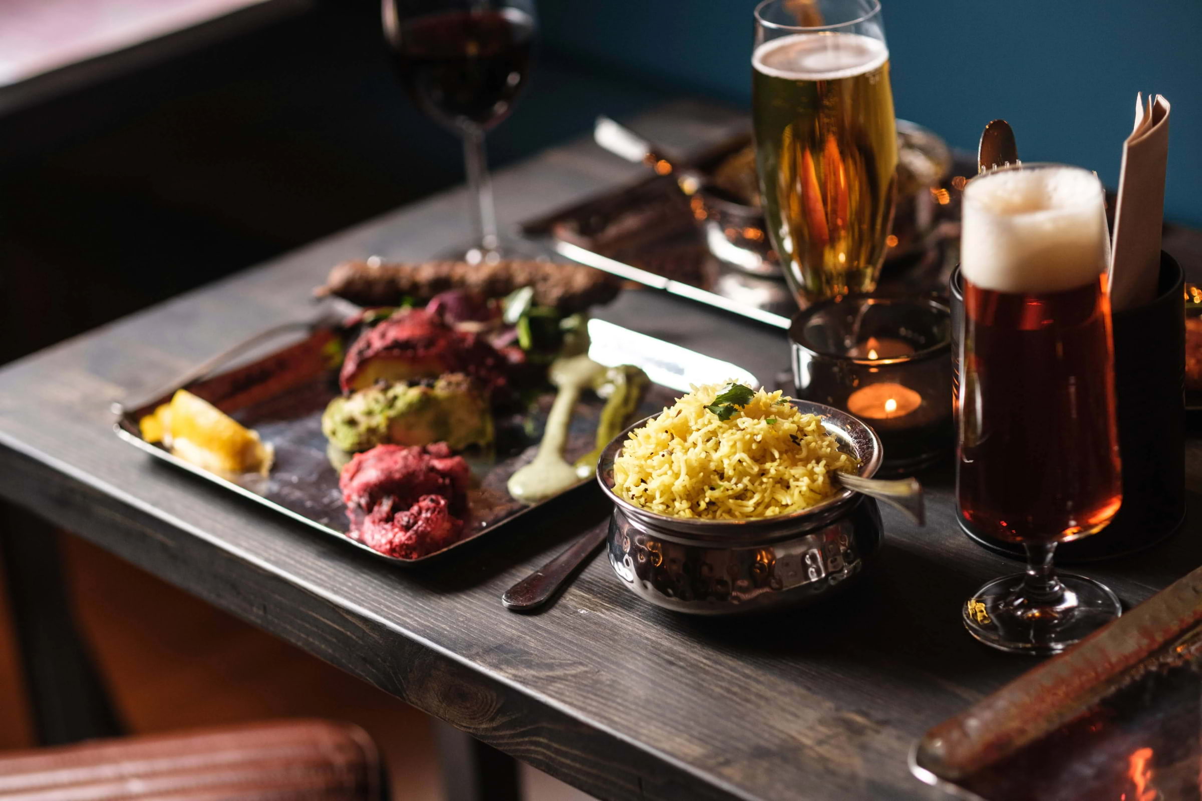 Indian food and drinks set out on a wooden restaurant table