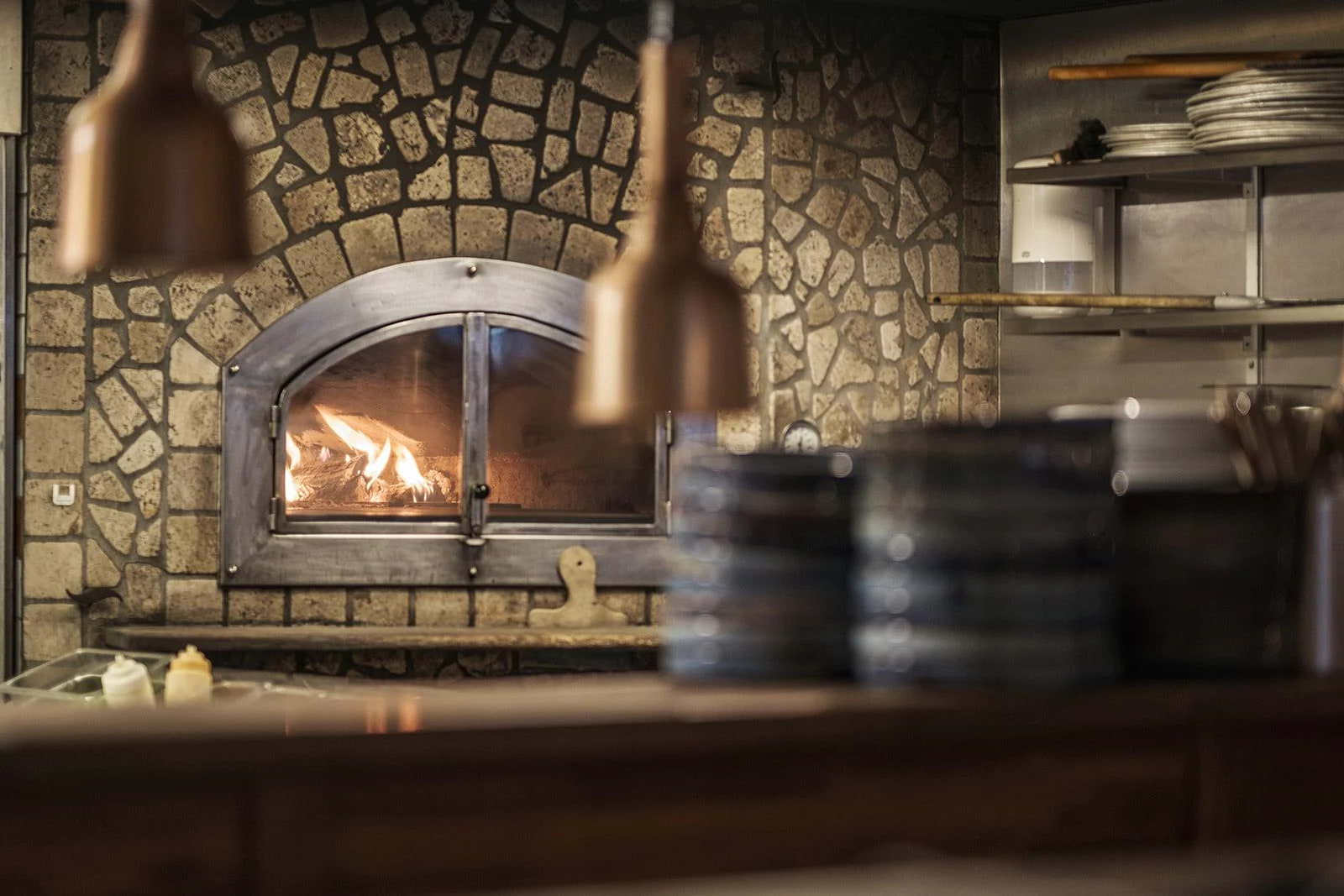 A pizza oven in an Italian restaurant with exposed stone walls