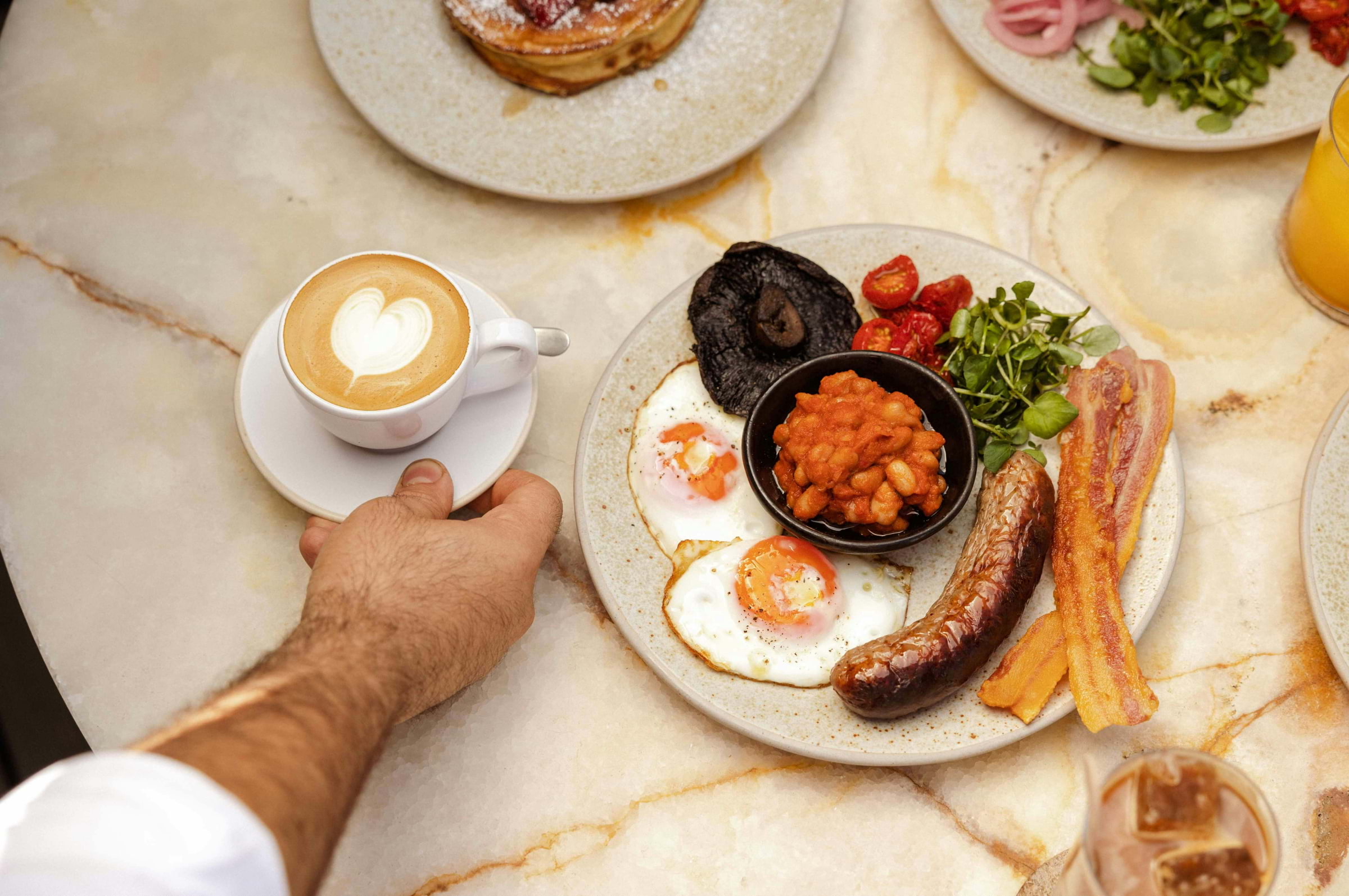 A full English breakfast on a marble table with coffee