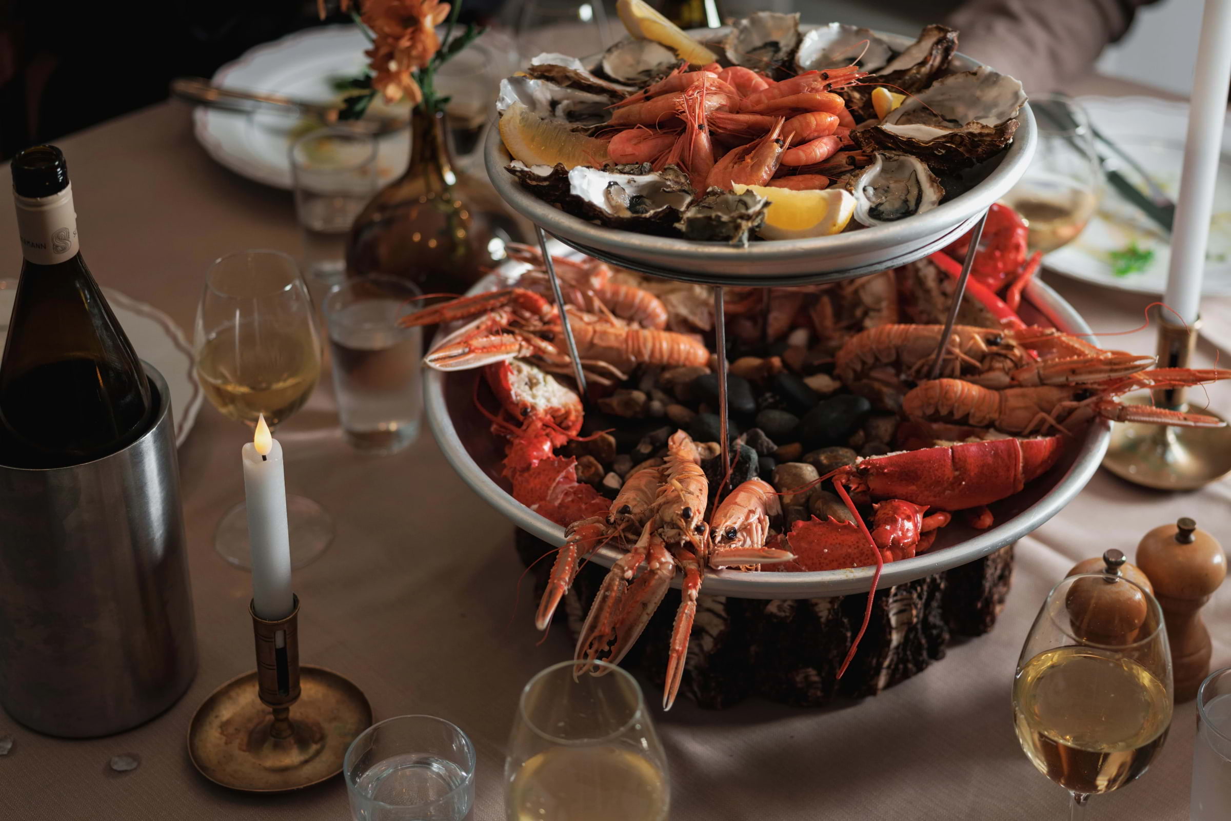 A lit candle and a tiered shellfish platter on a seafood restaurant table