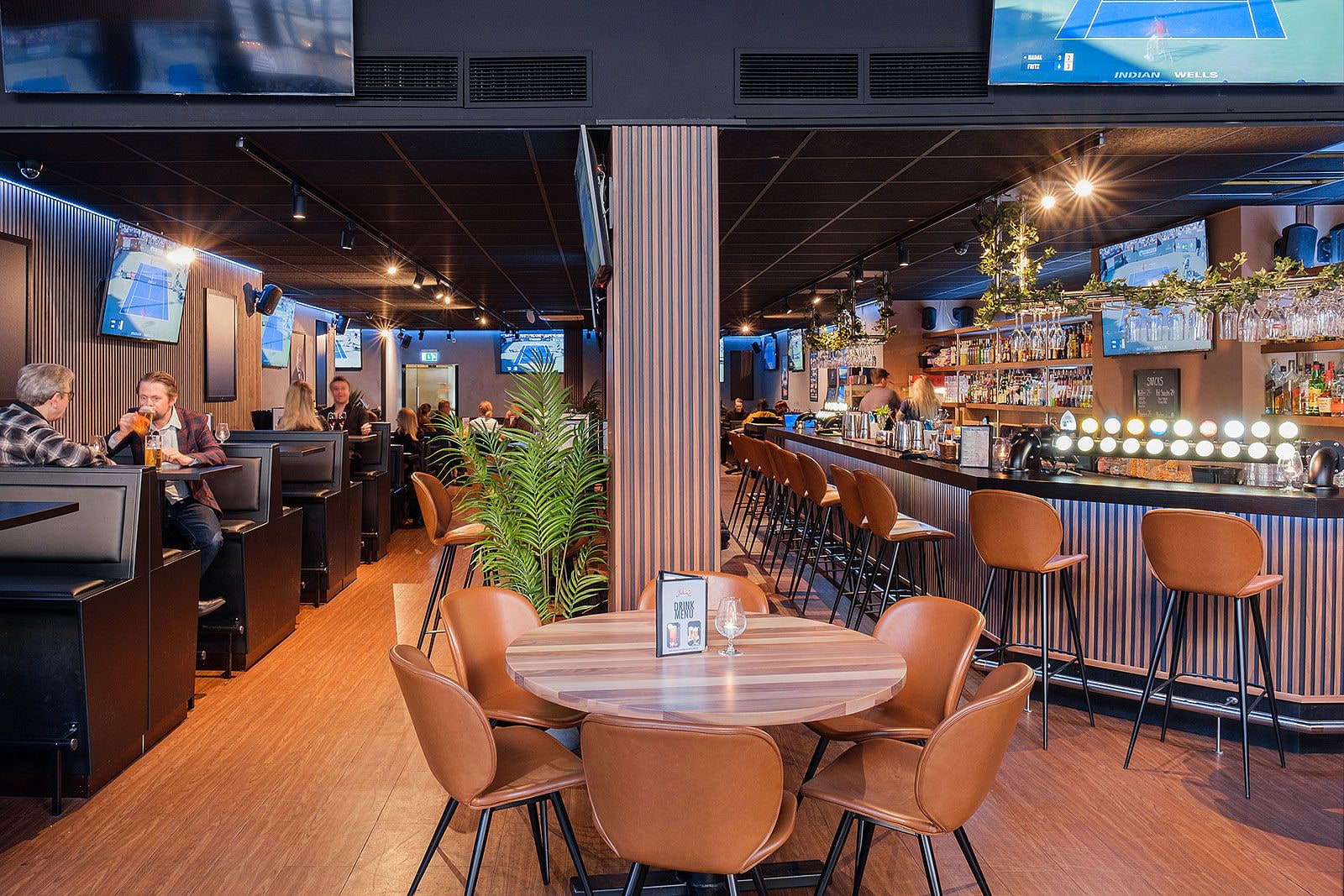 The interior of a sports bar with multiple screens and modern furniture