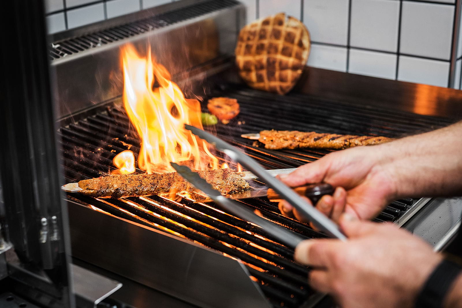 A cook grilling shish kebabs over a flame