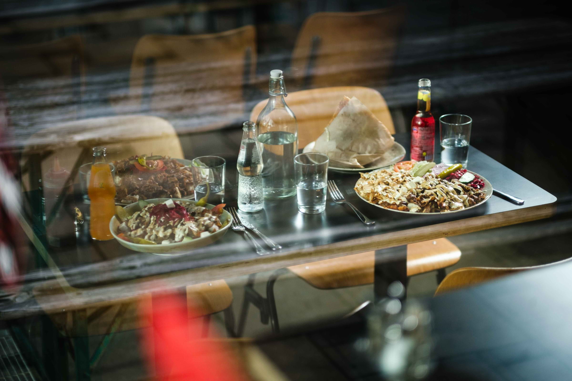 Different kebabs on a table seen through the kebab shop window